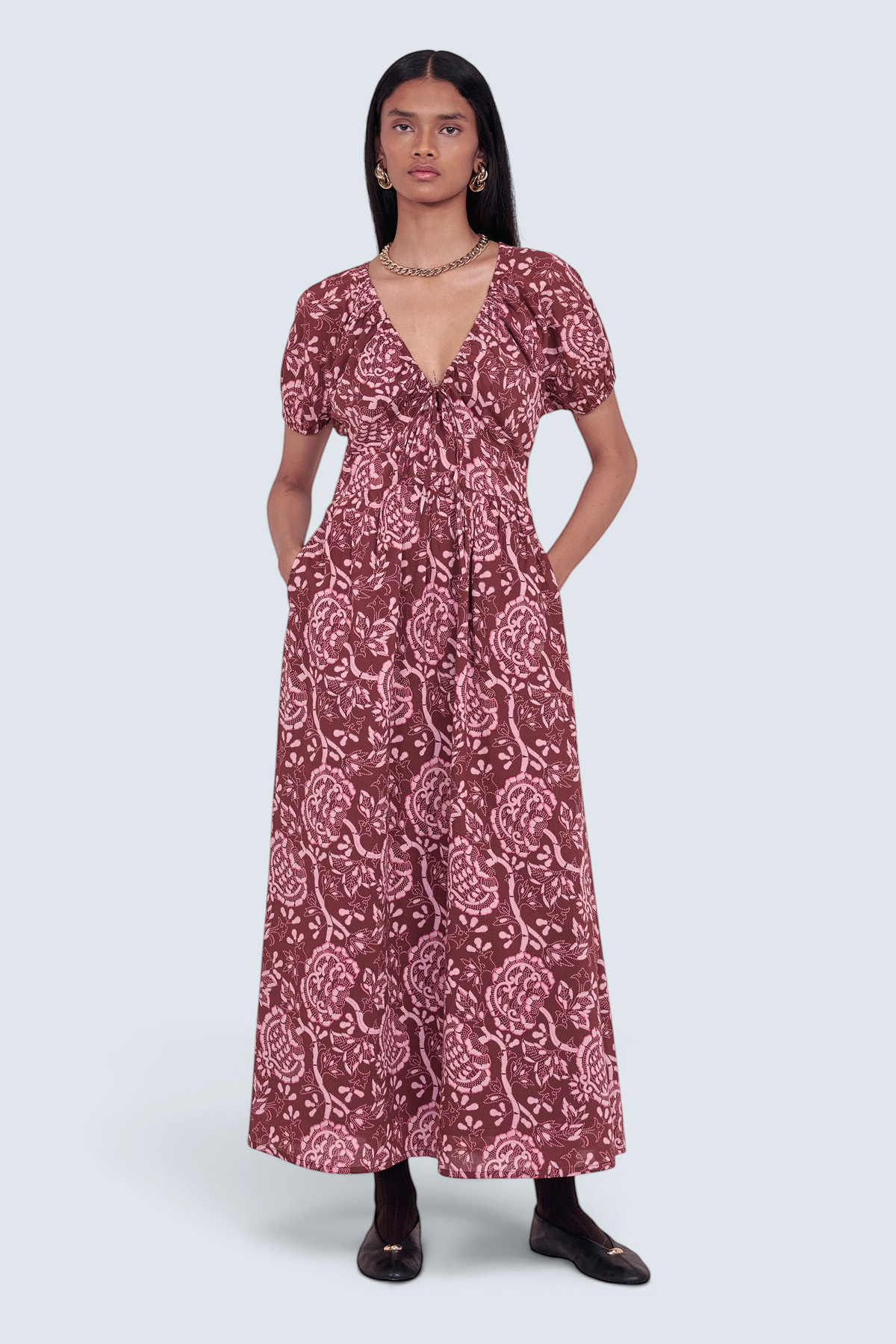 Front view of model standing. She is wearing the Norma dress in Coromandel print, featuring a drawstring neckline, elasticated sleeves, a flattering princess seam waist, and side-seam pockets.
