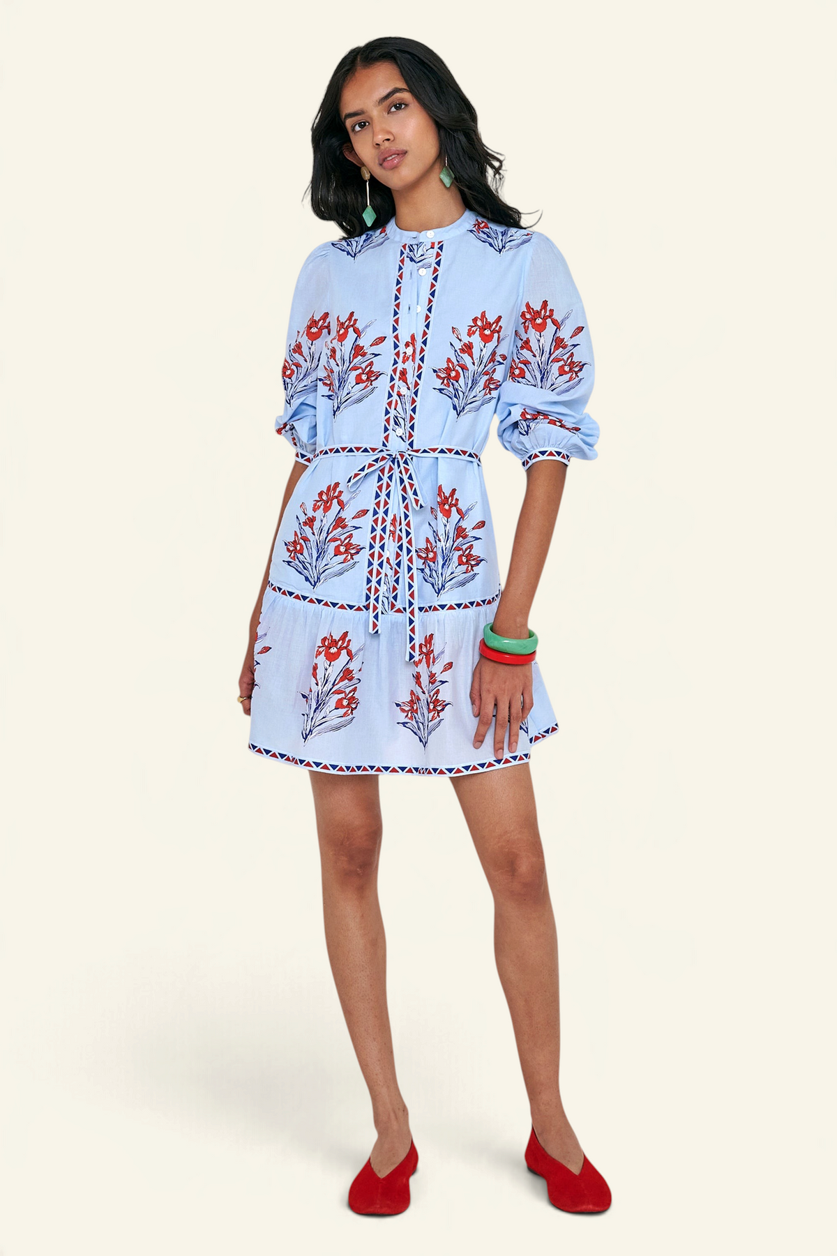 Front view of woman standing. She is wearing the Roma dress in the Brigitte print, featuring a mini shirtdress silhouette, contrast trim details, a detachable belt, and blooming iris floral motifs.