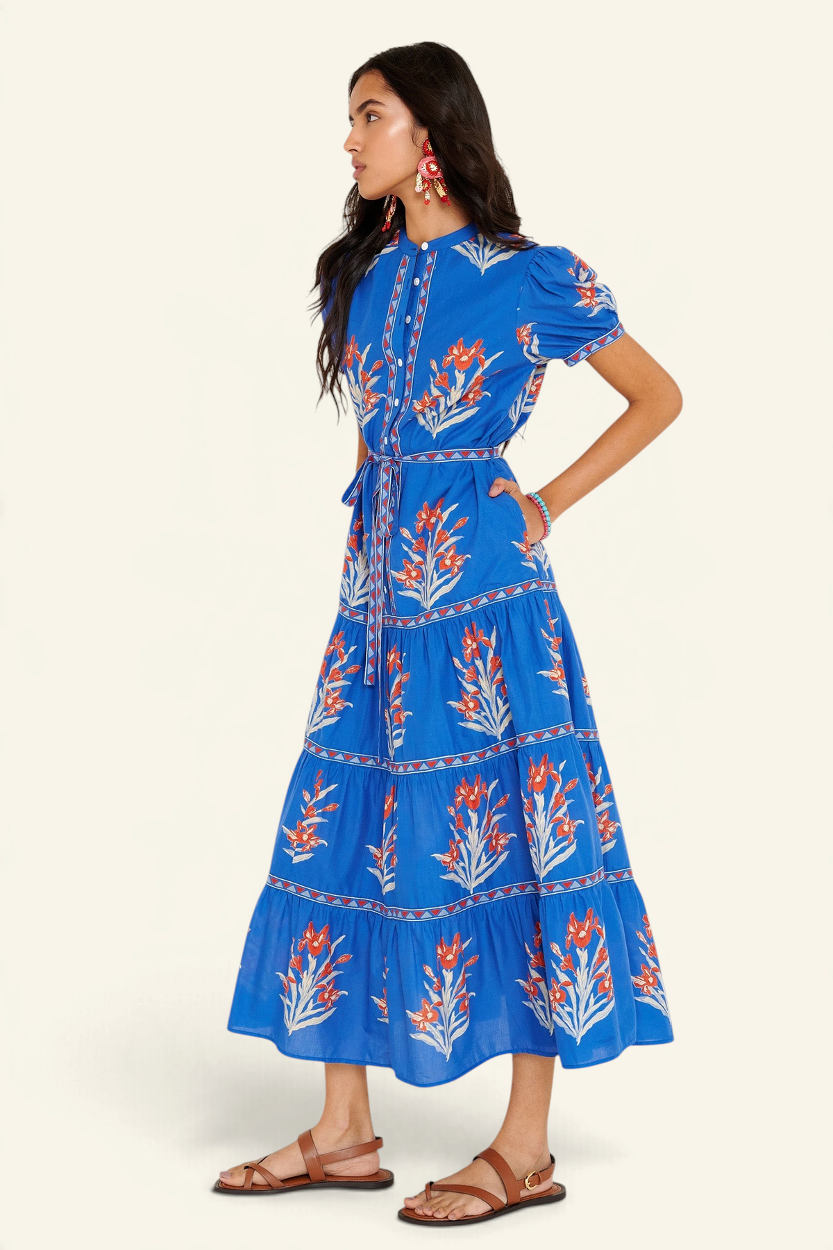 Side view of woman standing. She is wearing the Saylor dress in the Brigitte print, featuring a full-length shirtdress silhouette, tiered skirt, detachable belt, and hand-screen-printed iris floral motifs.