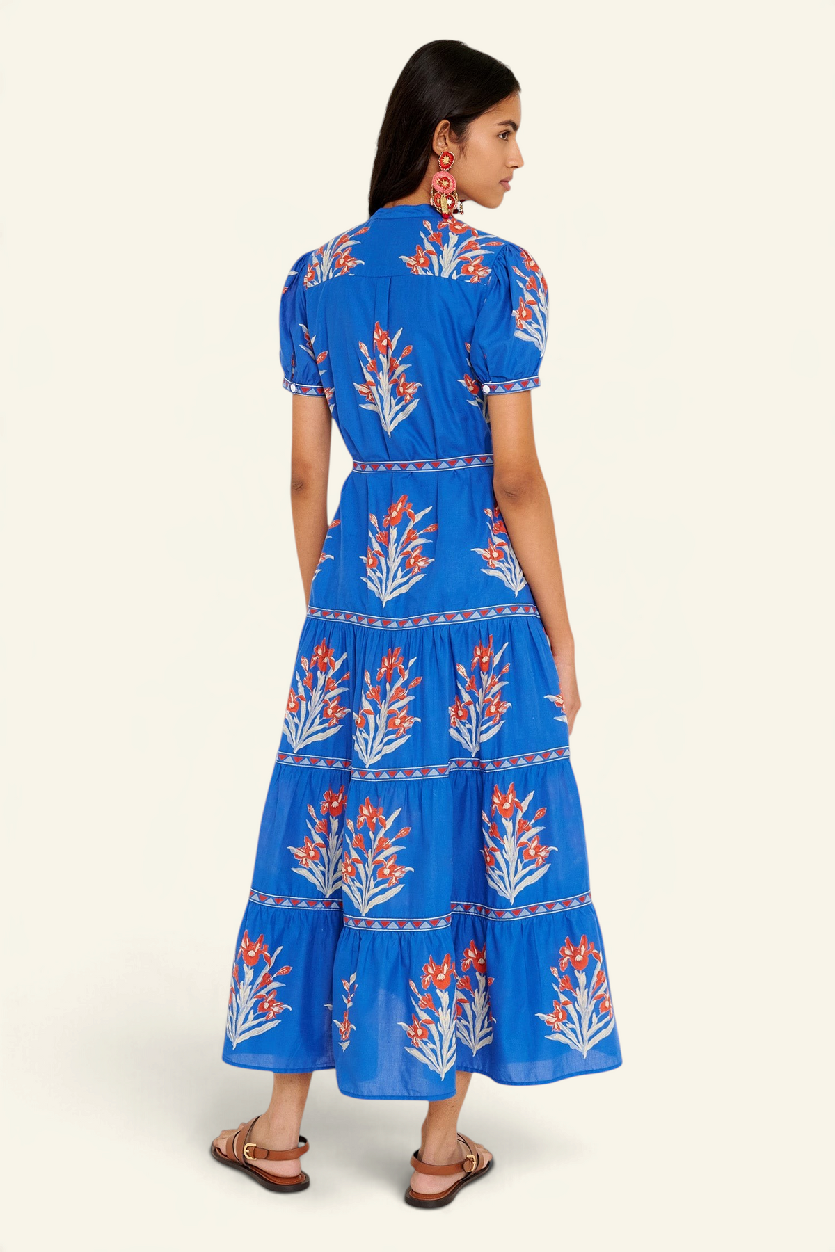 Back view of woman standing. She is wearing the Saylor dress in the Brigitte print, featuring a full-length shirtdress silhouette, tiered skirt, detachable belt, and hand-screen-printed iris floral motifs.