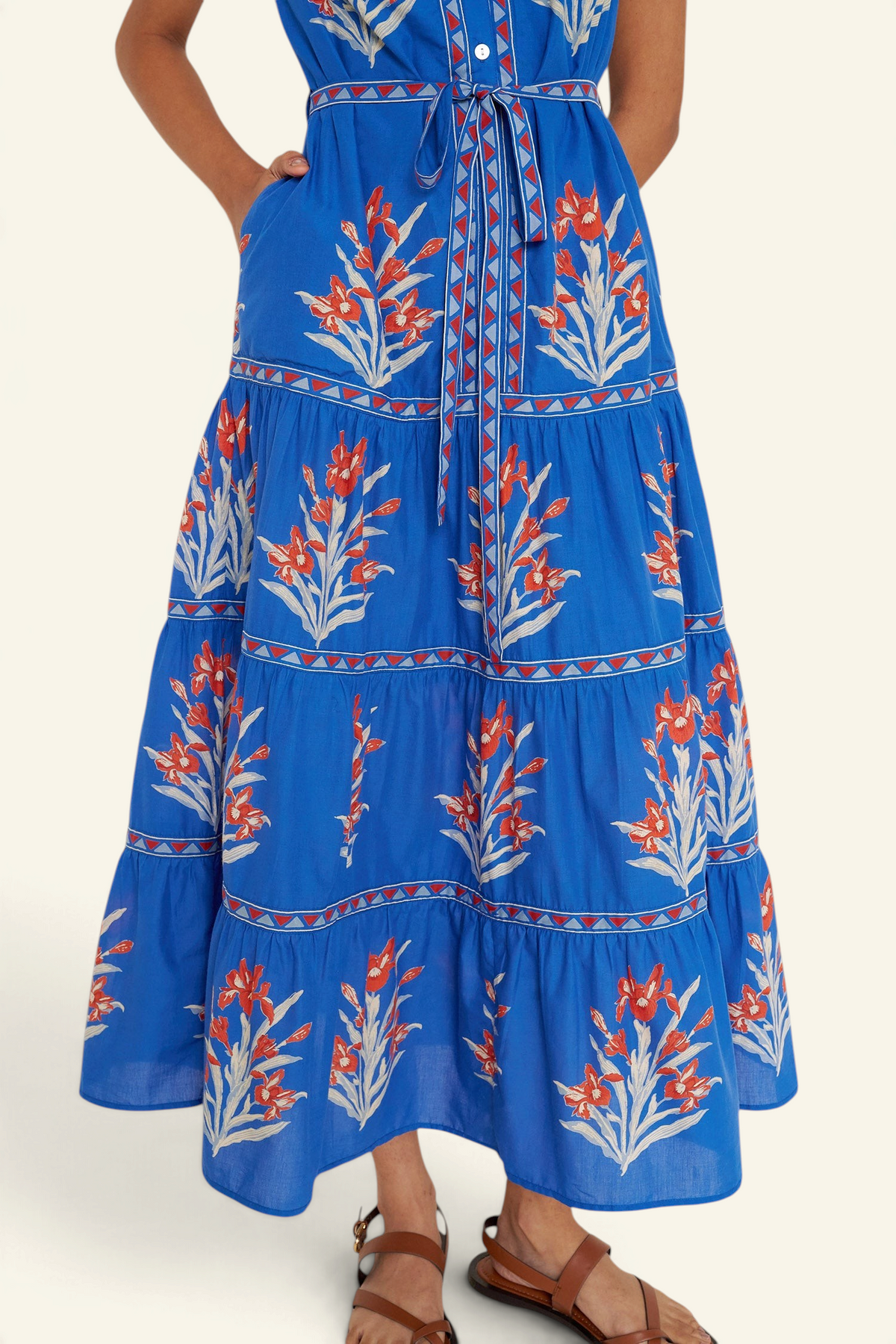 Front view close up of woman standing. She is wearing the Saylor dress in the Brigitte print, featuring a full-length shirtdress silhouette, tiered skirt, detachable belt, and hand-screen-printed iris floral motifs.