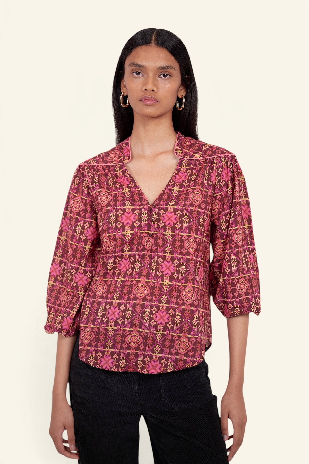 Front view of model standing. She is wearing Banjanan Vanessa top in mahogany cotton voile with a pink geometric floral needlepoint print and v-neckline.