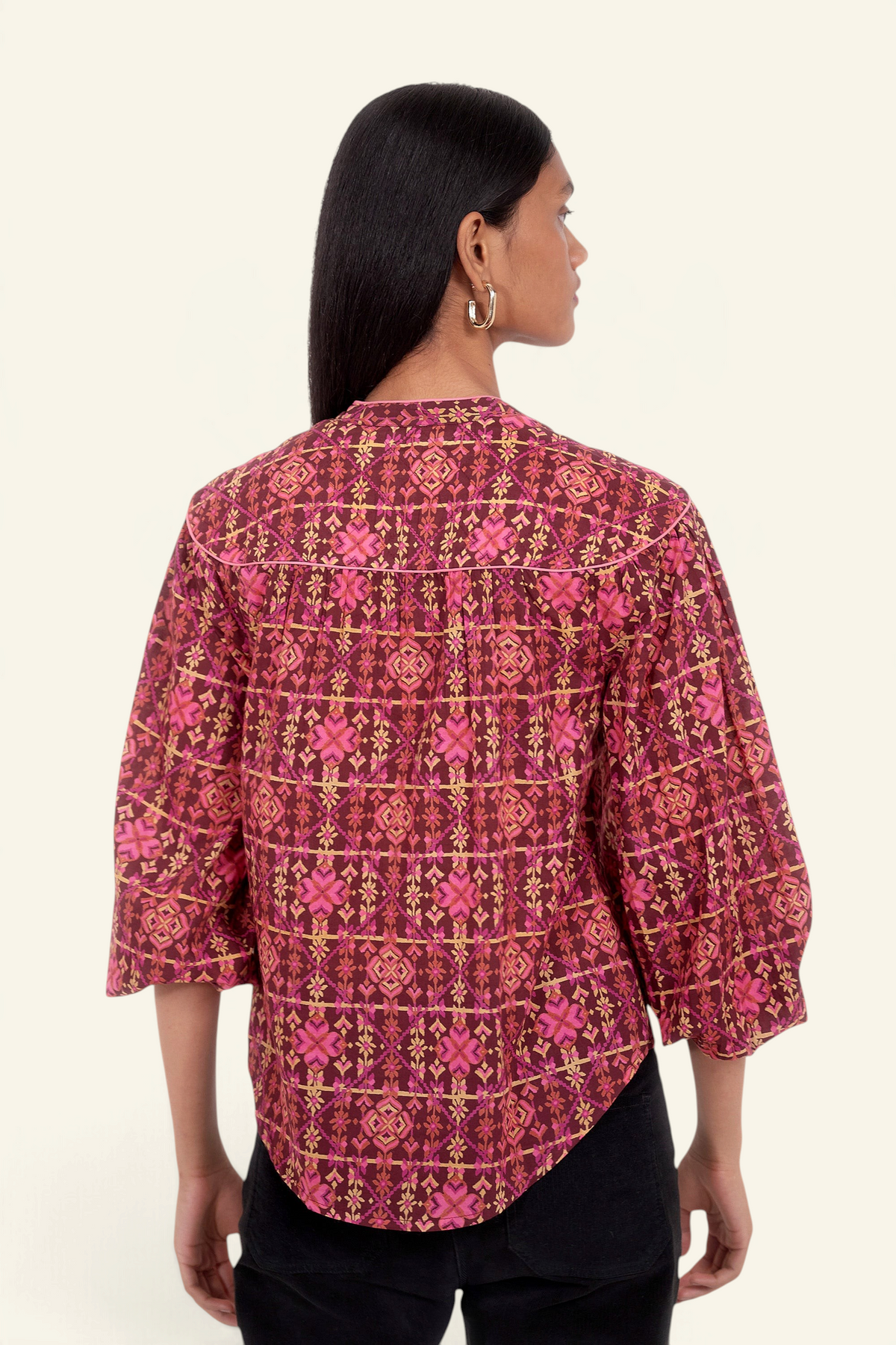Back view of model standing. She is wearing Banjanan Vanessa top in mahogany cotton voile with a pink geometric floral needlepoint print and v-neckline.