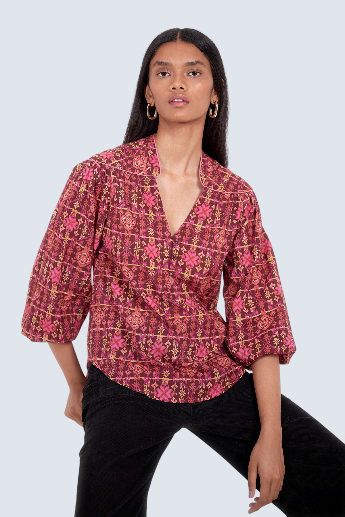 Front view of model. She is wearing Banjanan Vanessa top in mahogany cotton voile with a pink geometric floral needlepoint print and v-neckline.