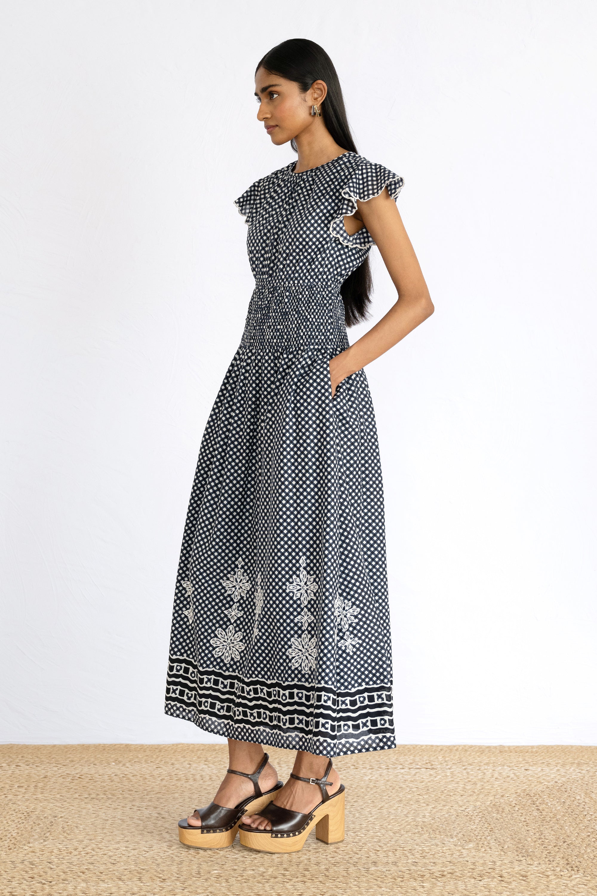 Side view of model wearing Aurelia Dress in Victorian Gingham Midnight print with a hands in pocket.