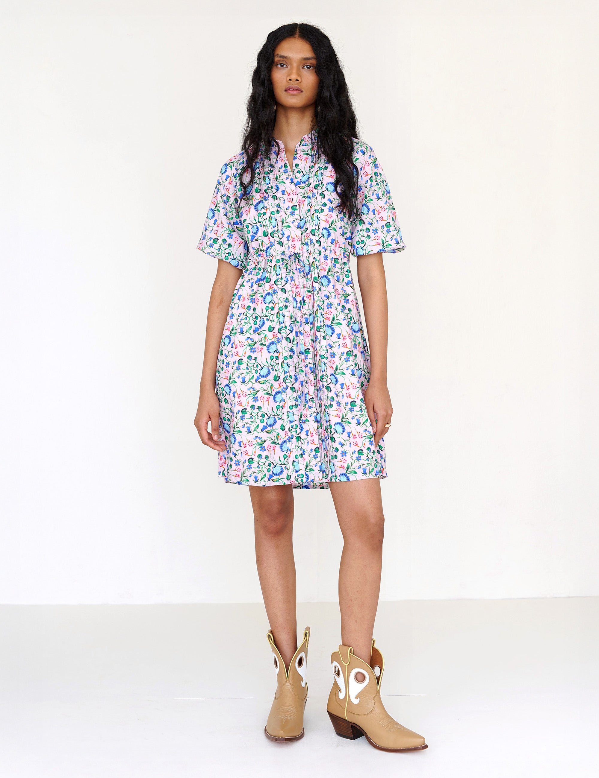 Front view of a woman standing. She is wearing the Benita shirtdress in Clam Garland print. It features a button-front placket, contrast-print trim, drawstring waist, and side-seam pockets.