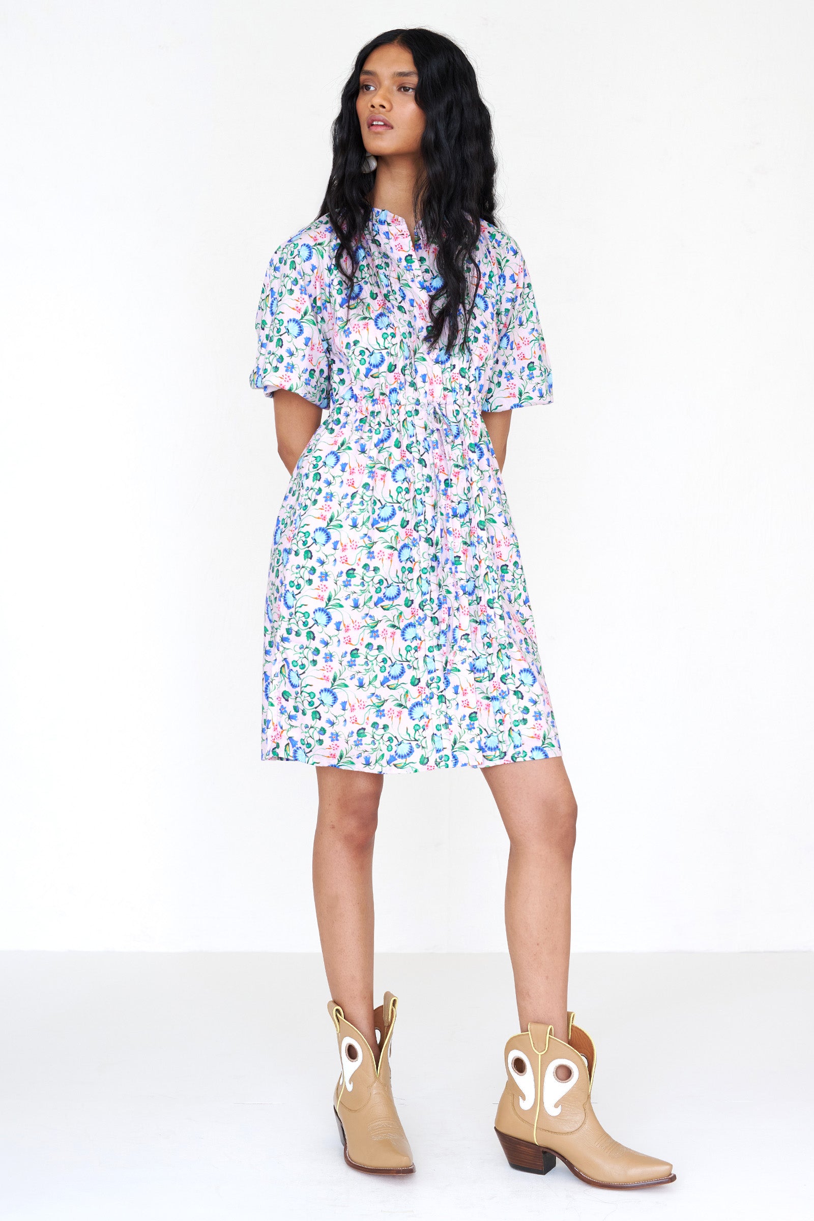 Front view of a woman standing. She is wearing the Benita shirtdress in Clam Garland print, featuring a buttoned front placket, drawstring waist, contrast-print trim and side-seam pockets.