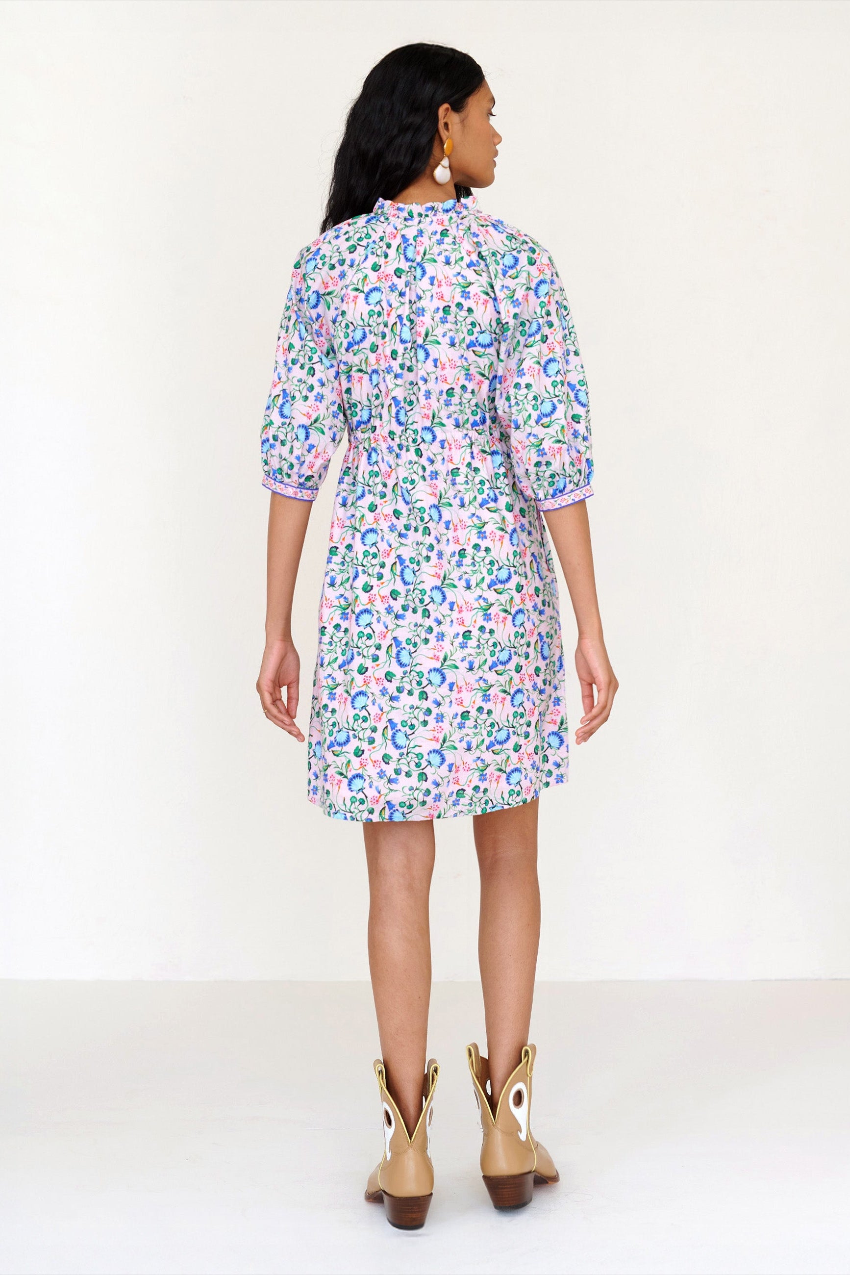 Back view of a woman standing. She is wearing the Benita shirtdress in Clam Garland print. It features a button-front placket, contrast-print trim, drawstring waist, and side-seam pockets.