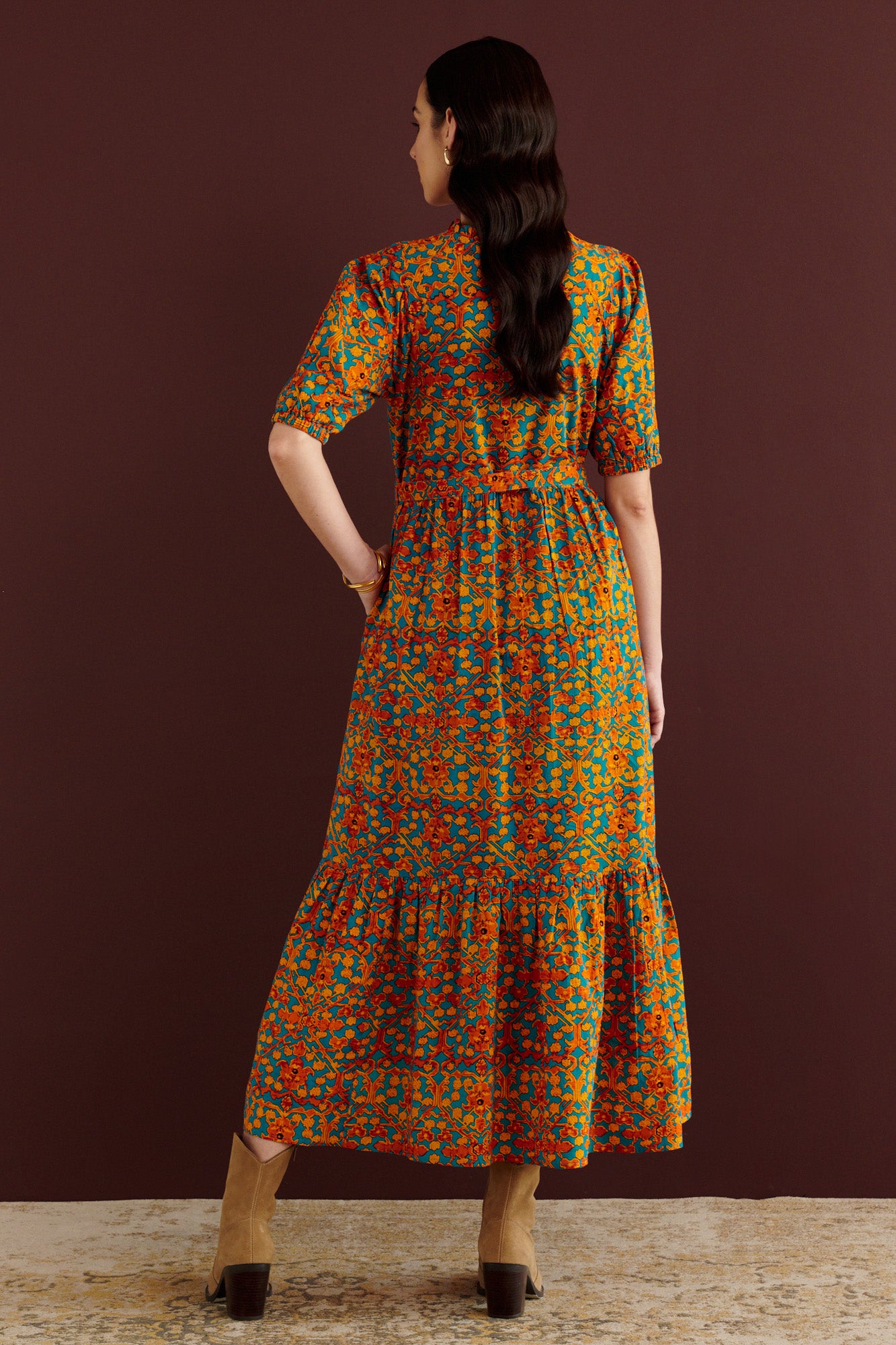 Back view of woman standing. She is wearing the Betty dress in Ottoman print. It has nipped waist, full gathered skirt, tucked raglan sleeves, cotton voile fabric, fabric tie belt, fully lined construction, and side-seam pockets.