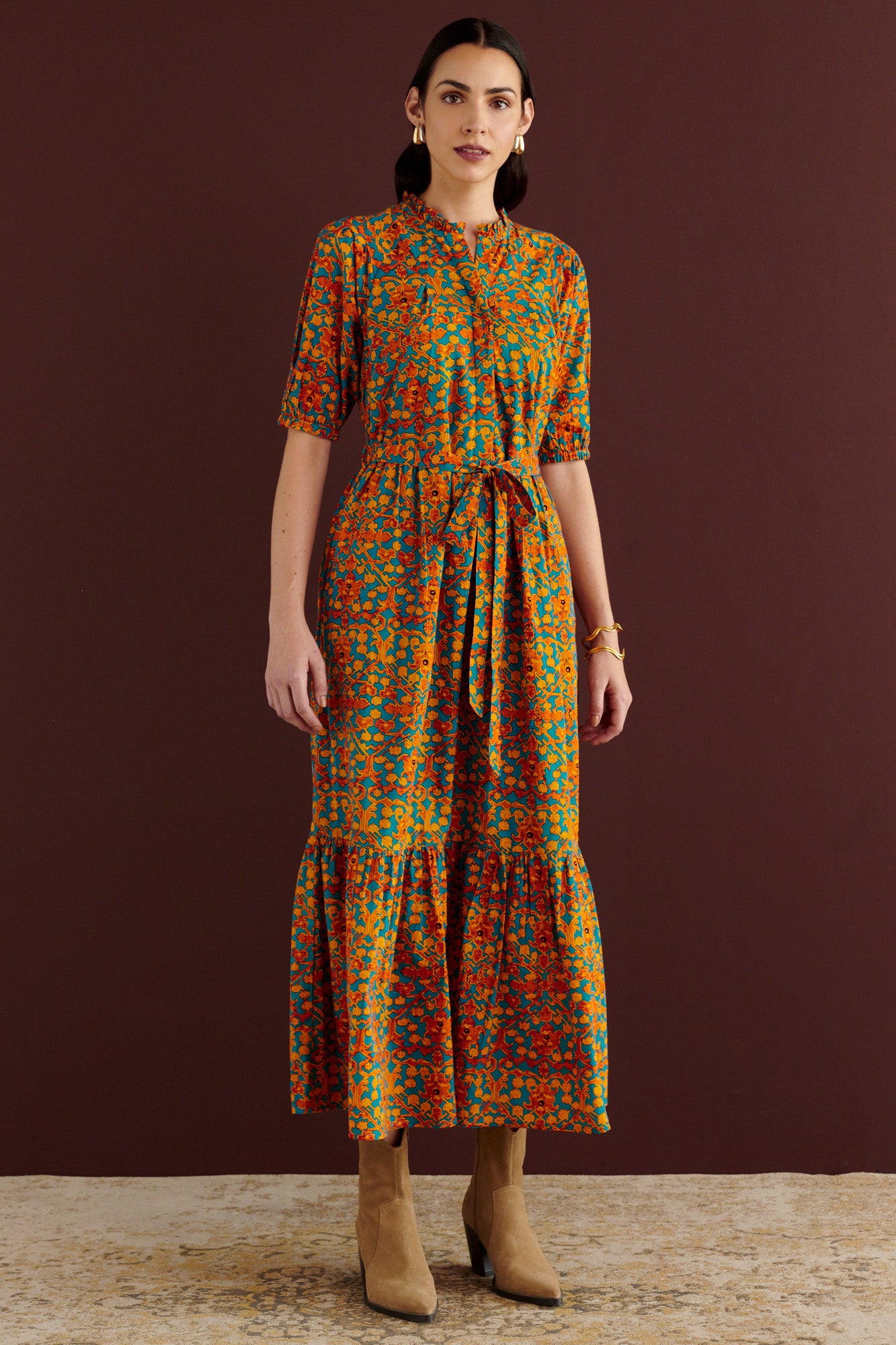 Front view of woman standing. She is wearing the Betty dress in Ottoman print. It has nipped waist, full gathered skirt, tucked raglan sleeves, cotton voile fabric, fabric tie belt, fully lined construction, and side-seam pockets.