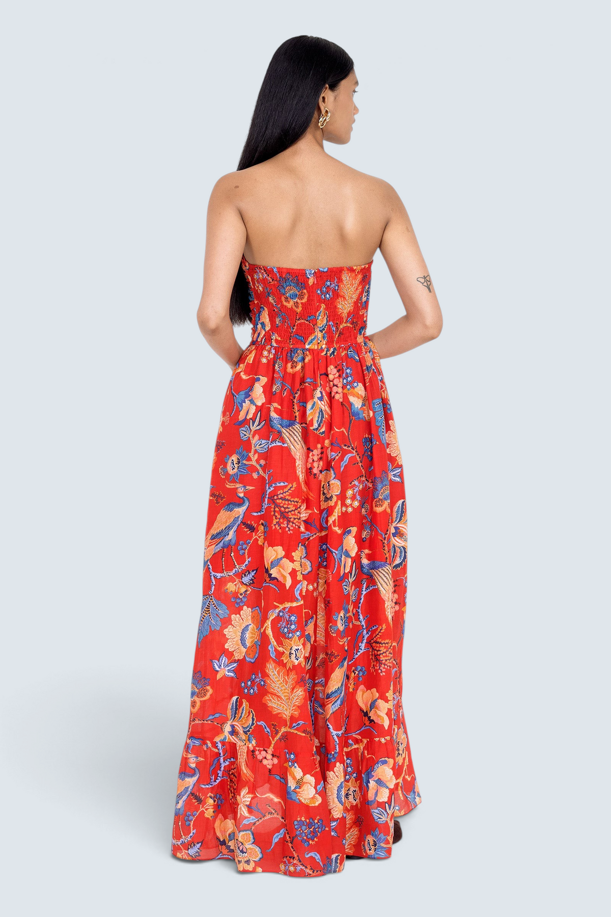 Back view of model standing. She is wearing the Bella dress in Chintz print. It features a full-length cascading skirt, subtle frill detail, ruched bodice, and smocked back.
