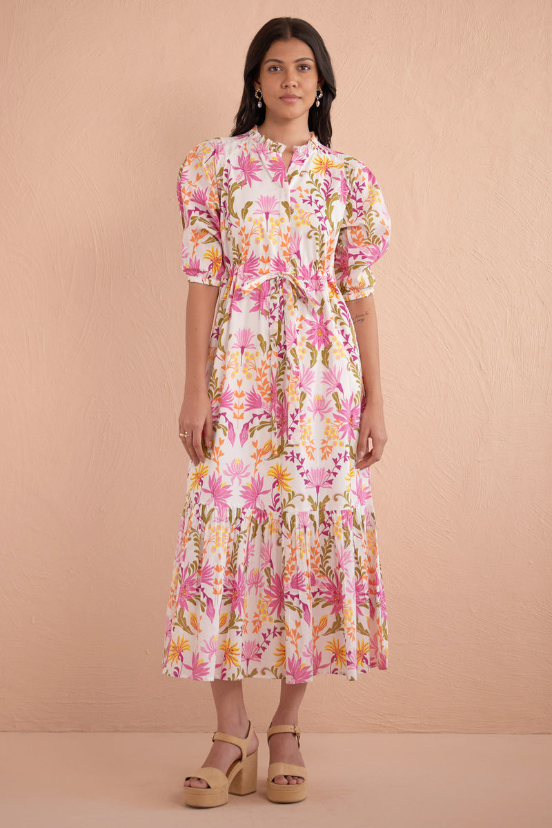 Front view of woman wearing Betty Dress in Hydra Garland Rose print, featuring a cinched waist, full gathered skirt, tucked raglan sleeves, concealed front button placket, drawstring waist, and side-seam pockets in bold sunset floral cotton voile.