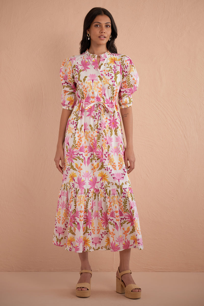 Front view of woman wearing Betty Dress in Hydra Garland Rose print, featuring a cinched waist, full gathered skirt, tucked raglan sleeves, concealed front button placket, drawstring waist, and side-seam pockets in bold sunset floral cotton voile.