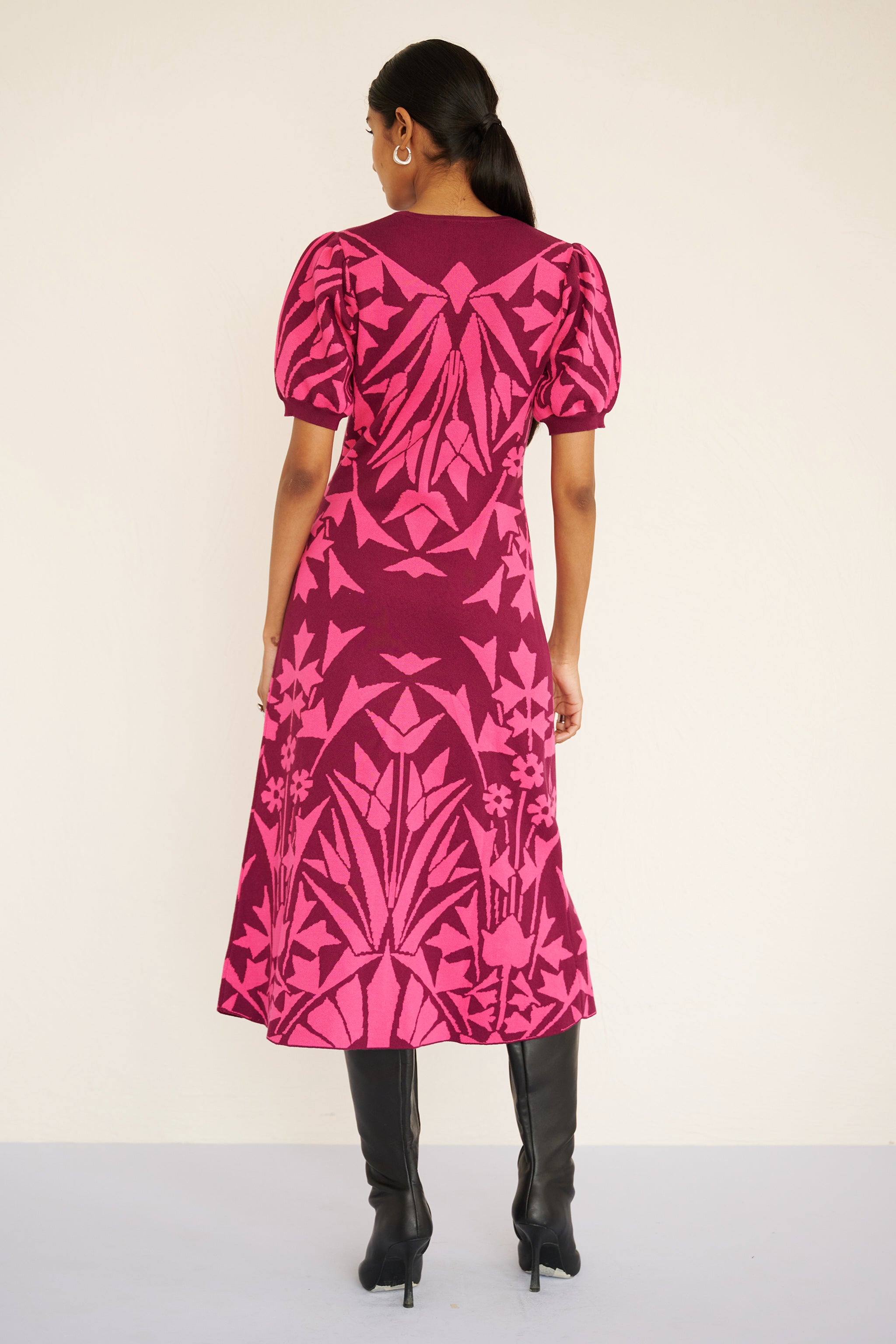 Back view of woman wearing a sleeveless jacquard midi dress with a fitted silhouette and hand-crocheted trim, featuring a textured, embroidery-inspired print.