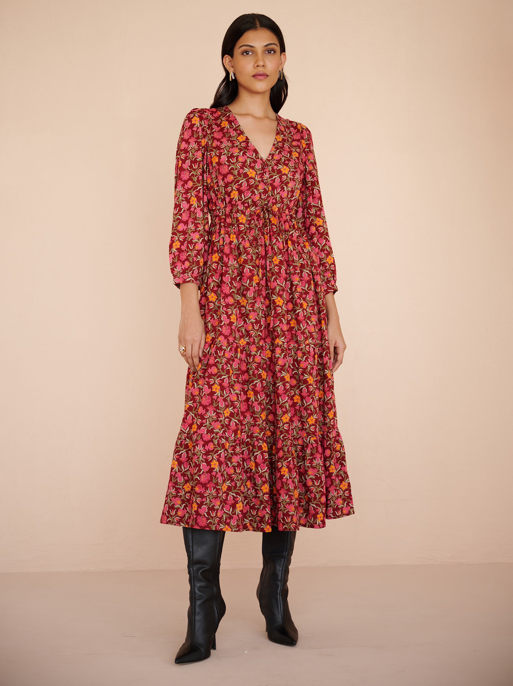 Front view of a model standing. She is wearing the Castor dress in eco-friendly viscose. It is featuring soft puff sleeves, a gathered drawstring skirt to the shin, and the Pomegranate Vine print in Azalea color. The dress is fully lined with side-seam pockets.