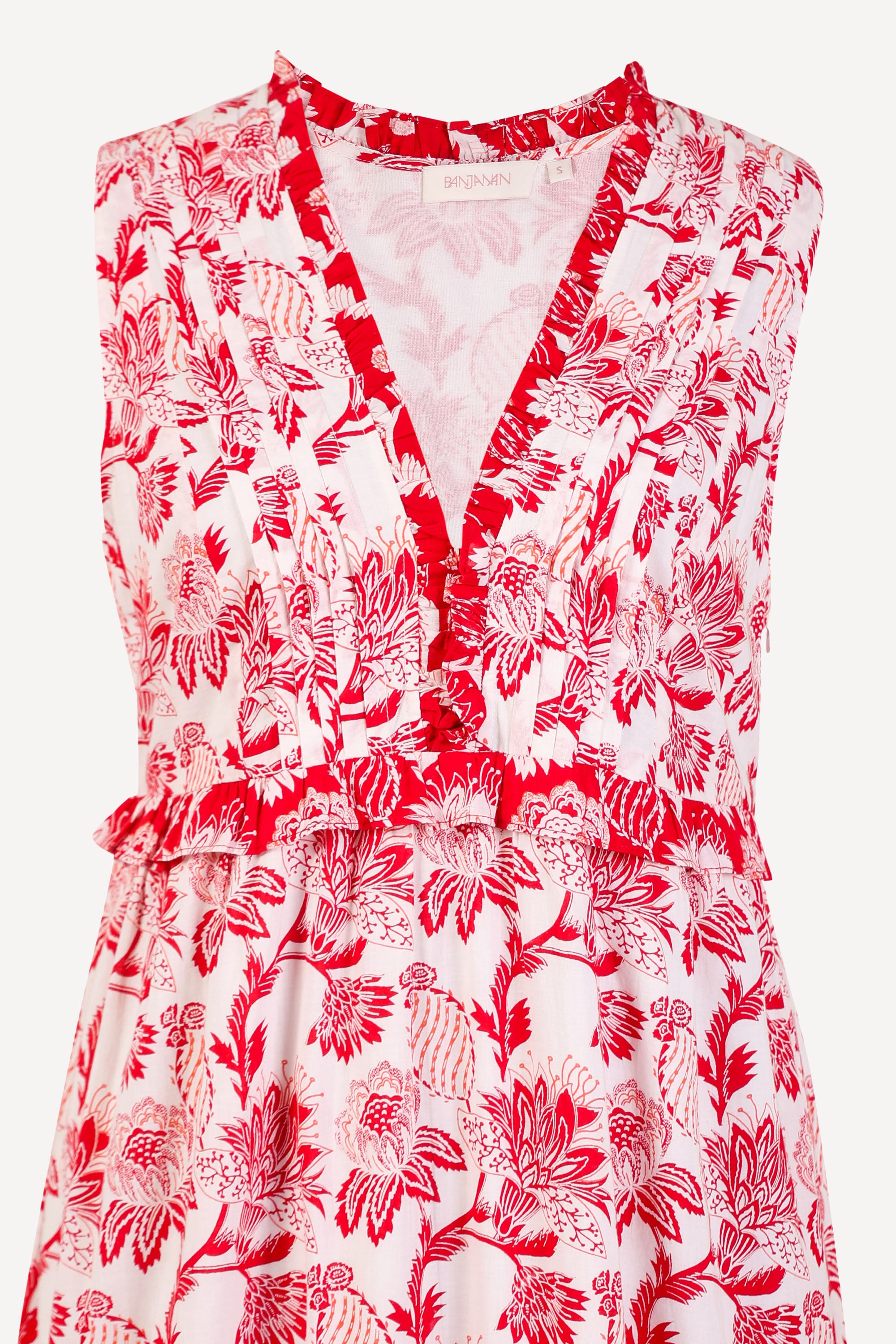 Front view close up of woman standing. She is wearing the Constance dress in the Lizzie print, featuring an A-line silhouette, pleated neckline, soft frill details, and floral vine motifs inspired by Provence.