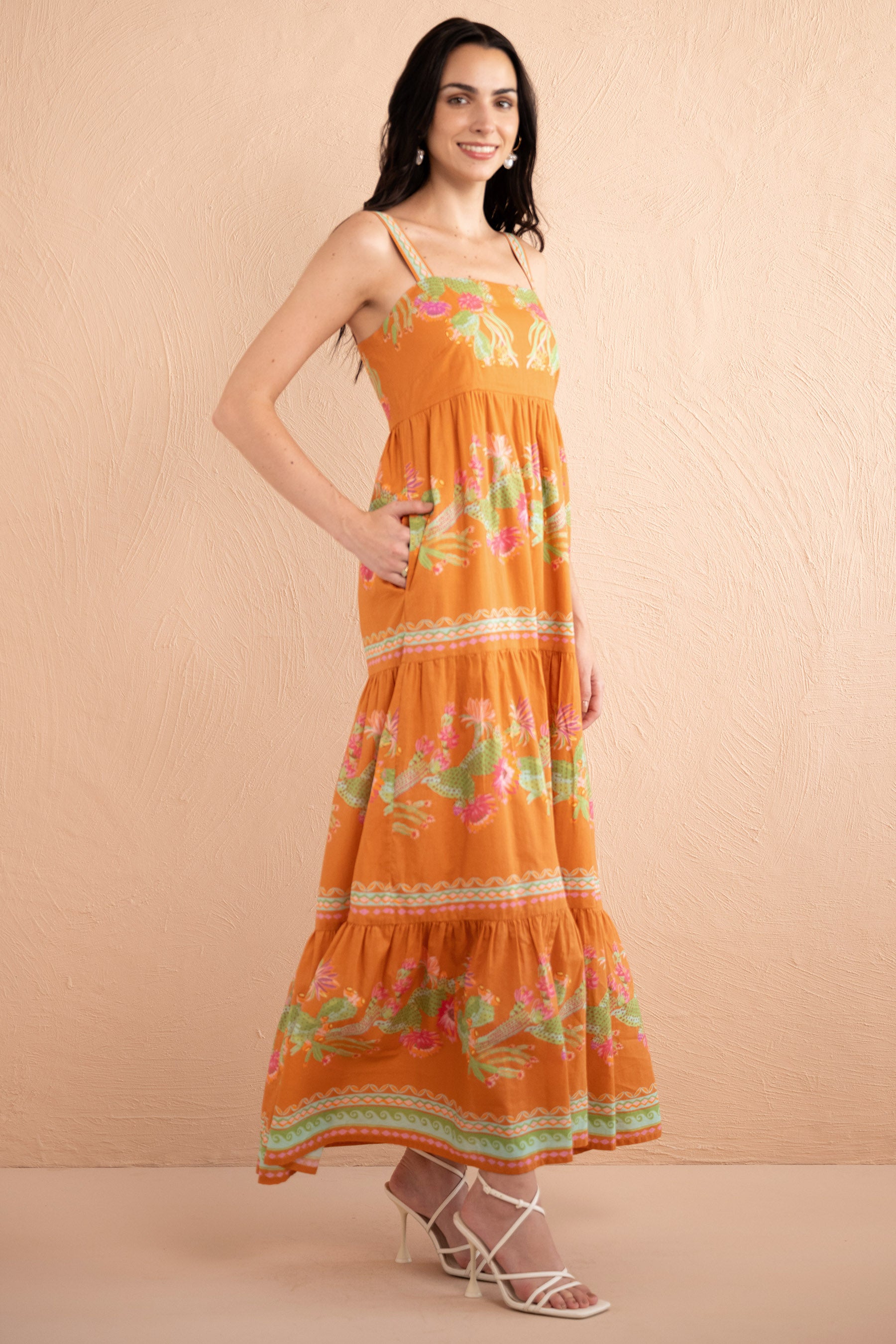 Side view of model wearing a full length Daniella dress in Calypso Cacti print in Caramel color with hand in pocket.