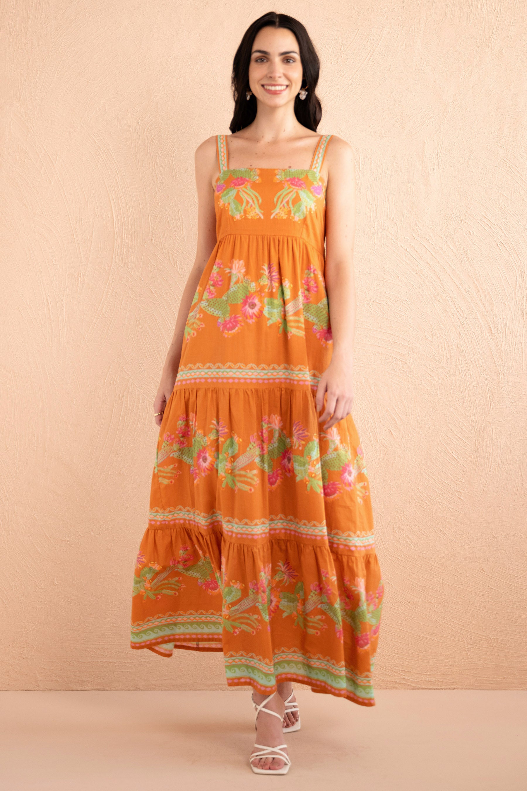 Front view of model stepping forward wearing a full length Daniella dress in Calypso Cacti print in Caramel color.