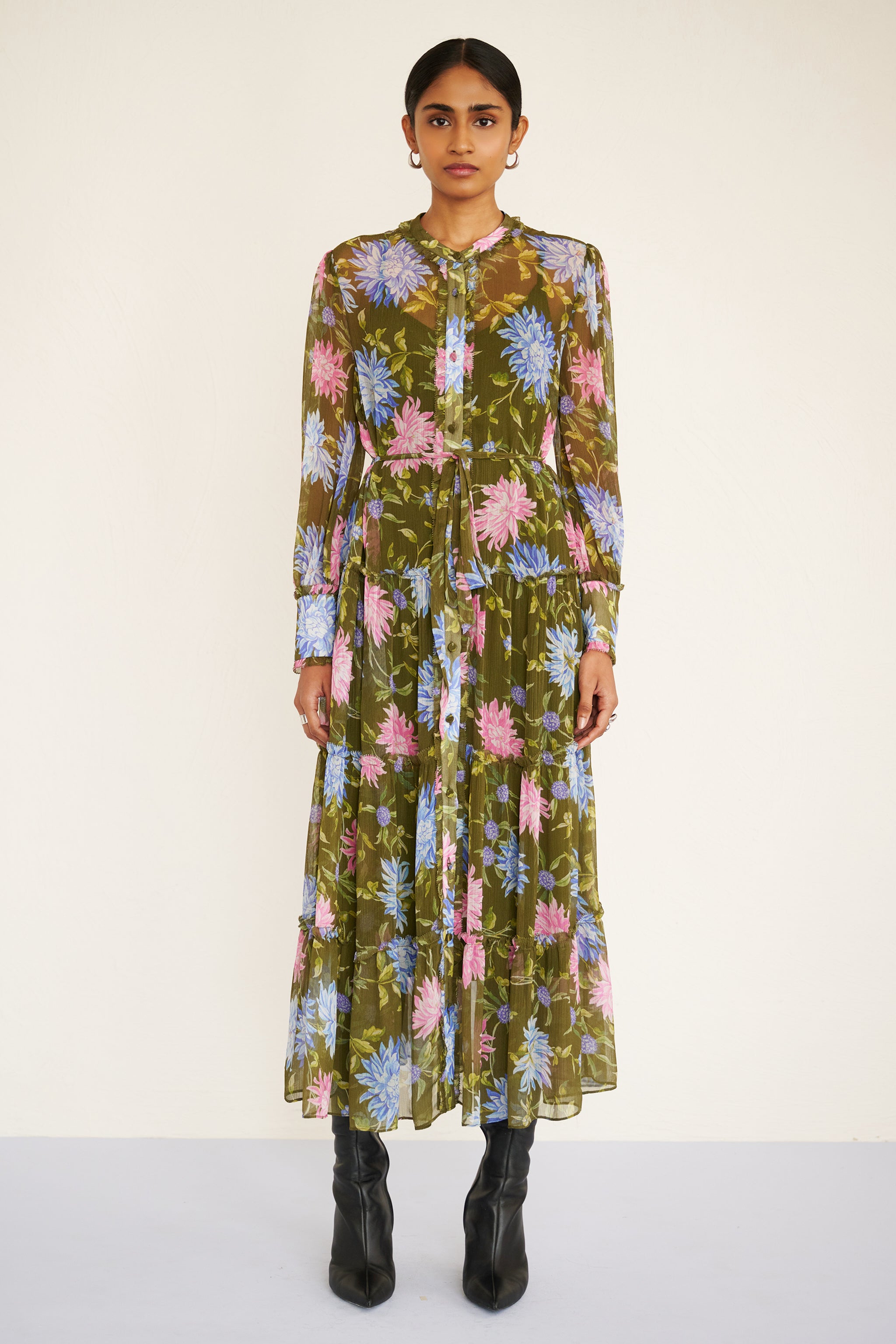 Front view of woman wearing a long-sleeve chiffon midi dress with sheer sleeves, ruffle details, fabric buttons, and a painterly floral print, styled with a detachable belt.