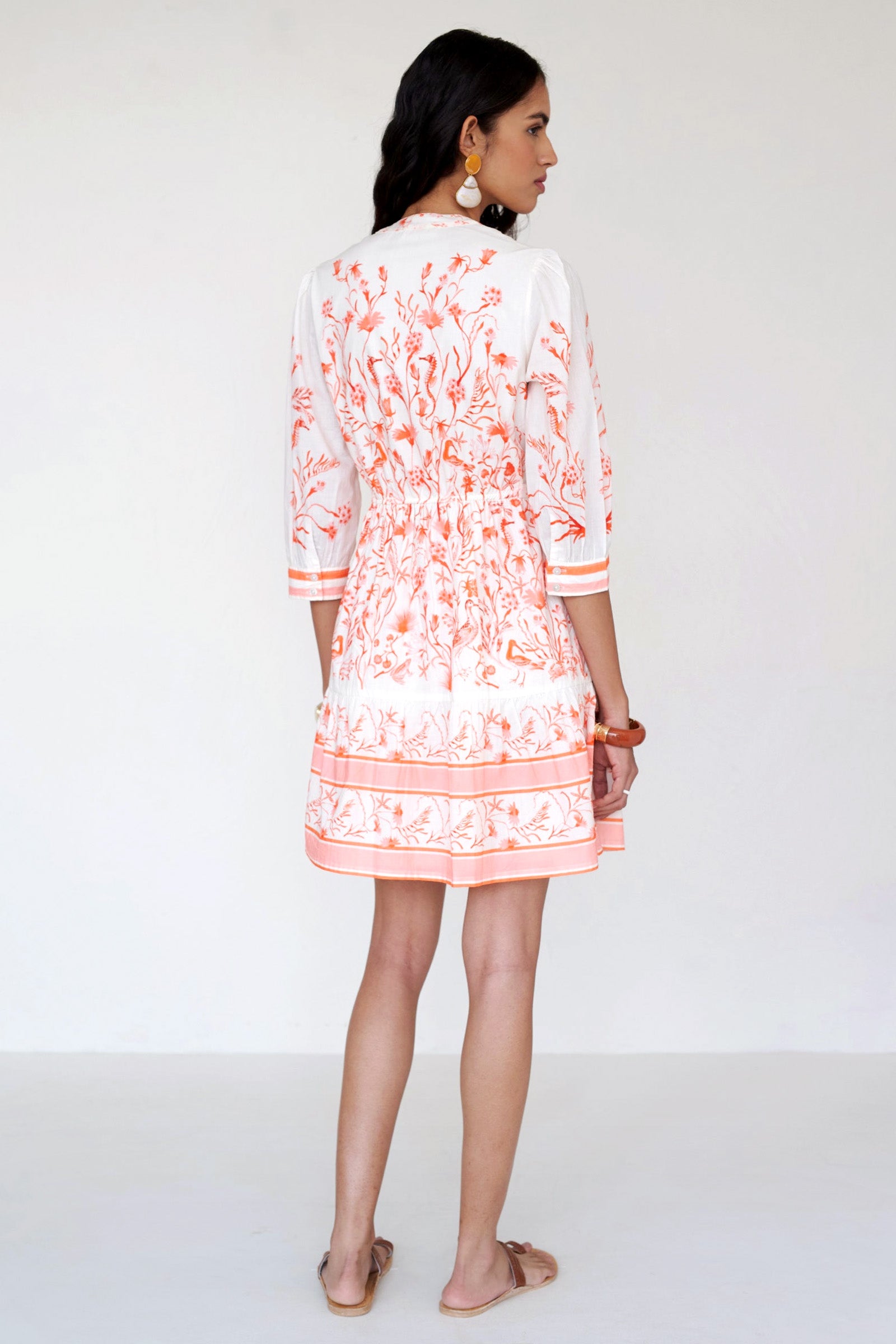 Back side view of a woman standing wearing the Gizela shirtdress in Tidepool print, featuring a round neckline, buttoned cuffs & self-tie waist belt.