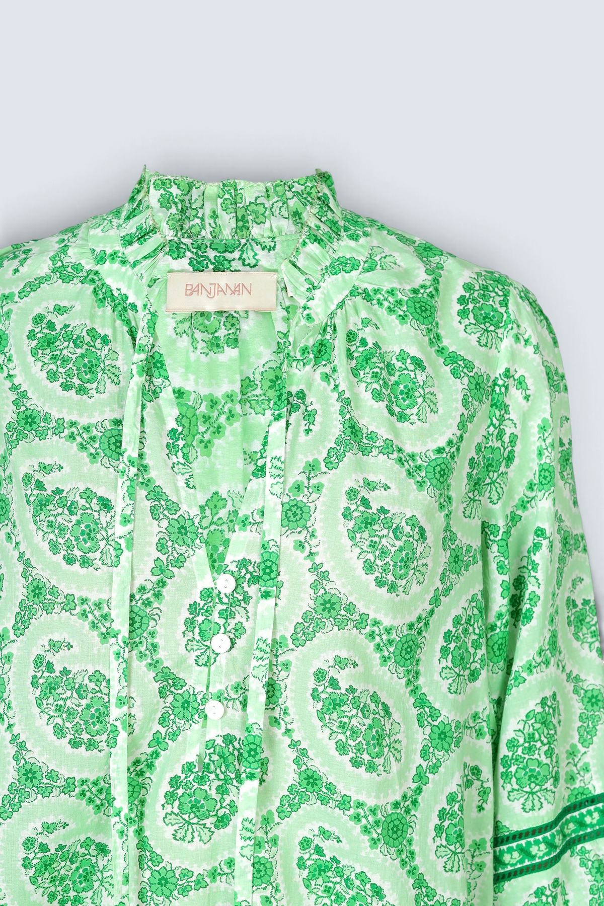 Ghost image of a green paisley Lorna blouse with ruffled tie neckline, button front, and contrast-trimmed sleeves.