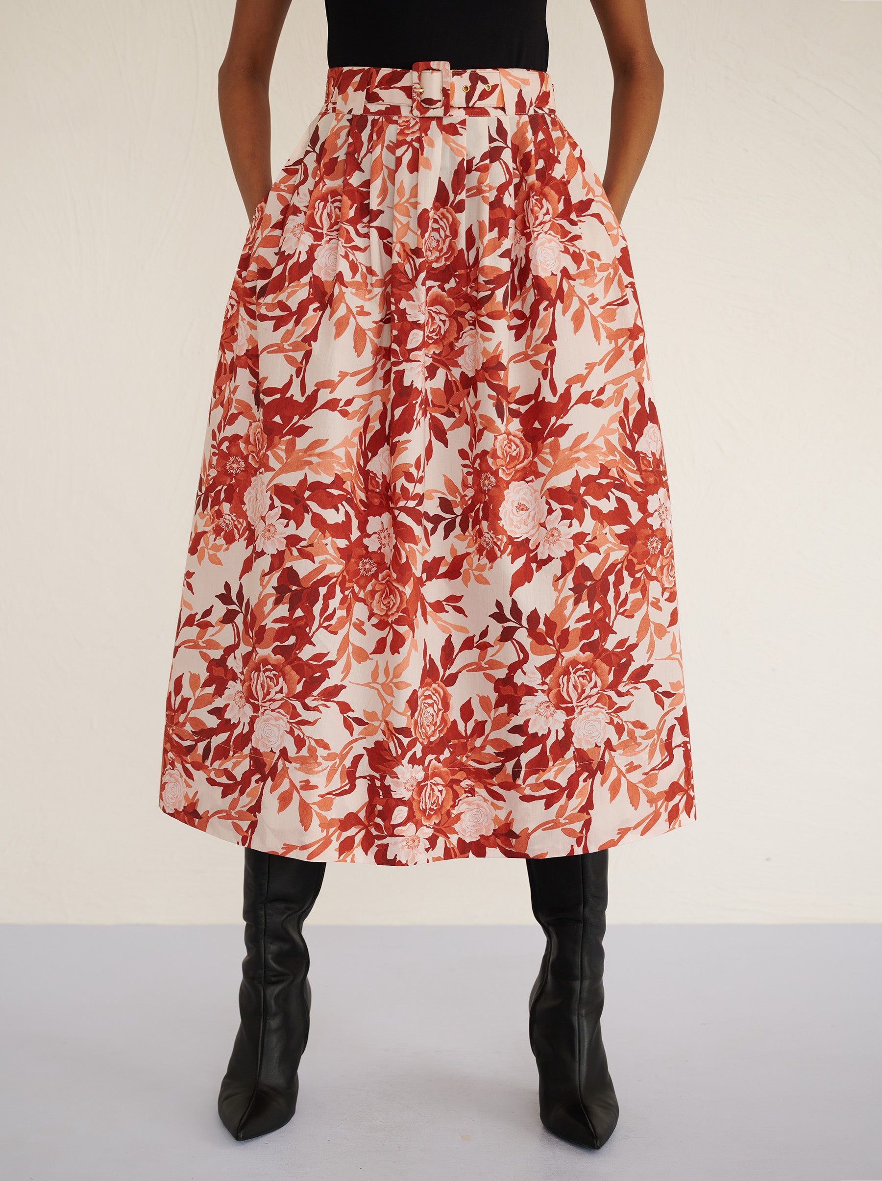 Front view close up of a model standing. She is wearing the Magdalena skirt in the Bibi Rose print. It is featuring soft all-around pleats, side-seam pockets, and a back zipper fastening for a classic, flattering silhouette.