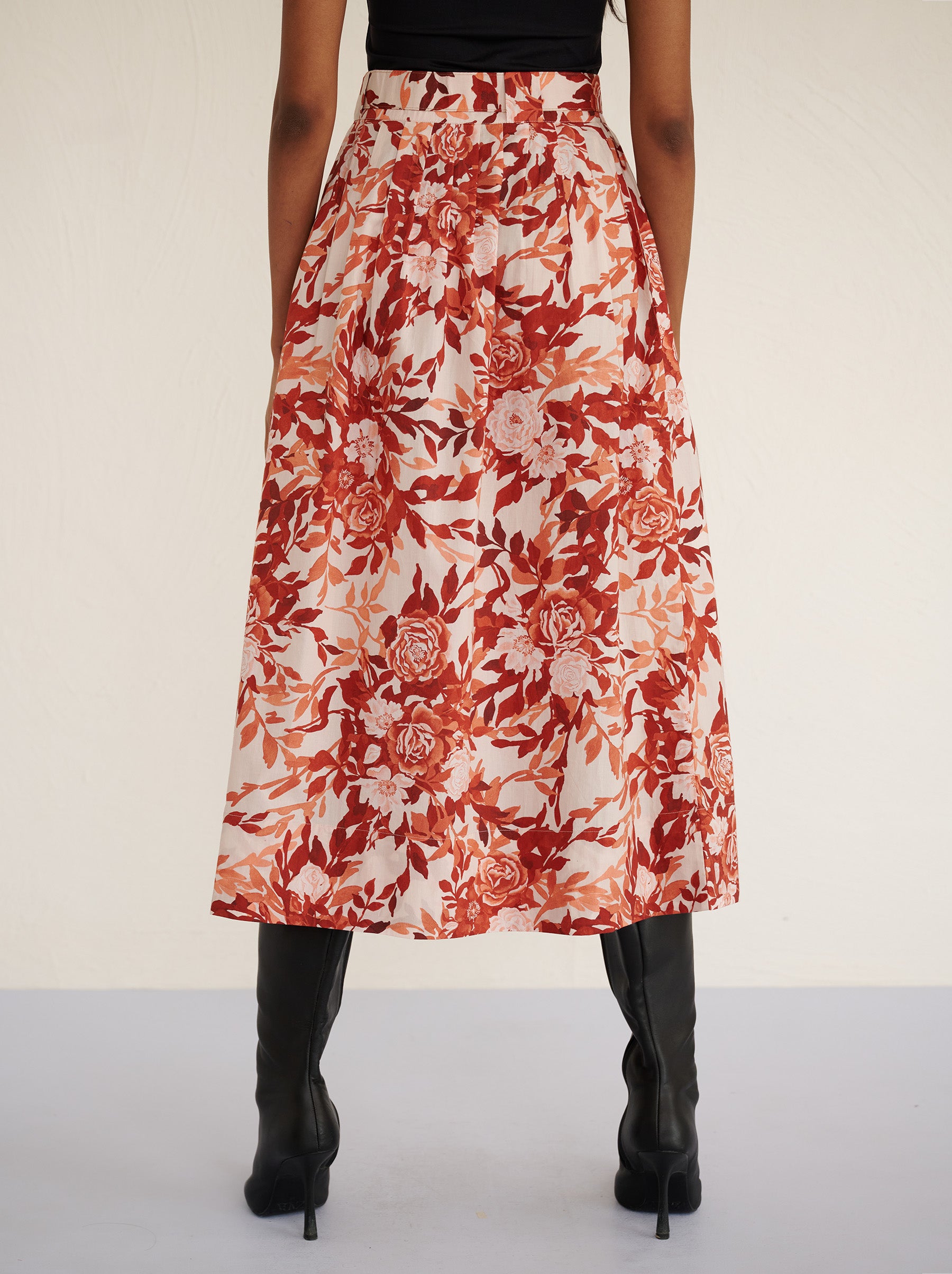 Back view close up of a model standing. She is wearing the Magdalena skirt in the Bibi Rose print. It is featuring soft all-around pleats, side-seam pockets, and a back zipper fastening for a classic, flattering silhouette.
