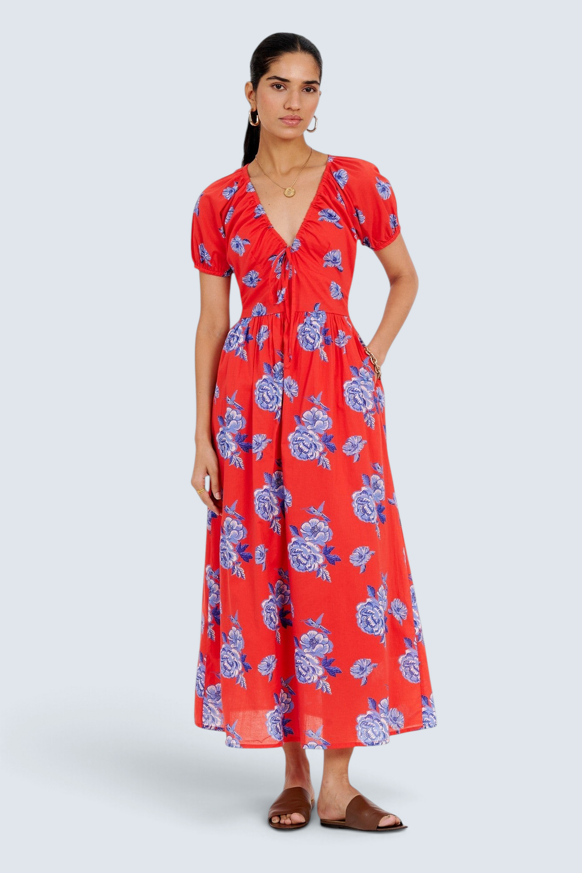 Banjanan Norma dress in poppy red with blue floral print, featuring a drawstring neckline and puff sleeves.