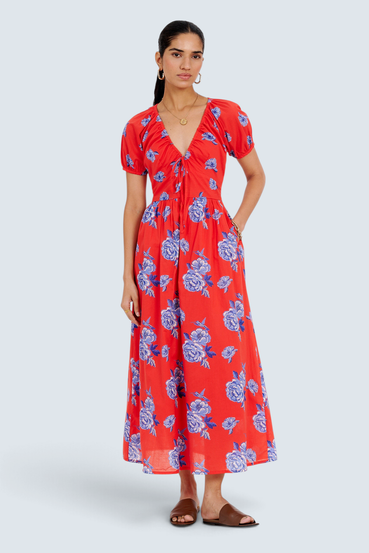 Banjanan Norma dress in poppy red with blue floral print, featuring a drawstring neckline and puff sleeves.
