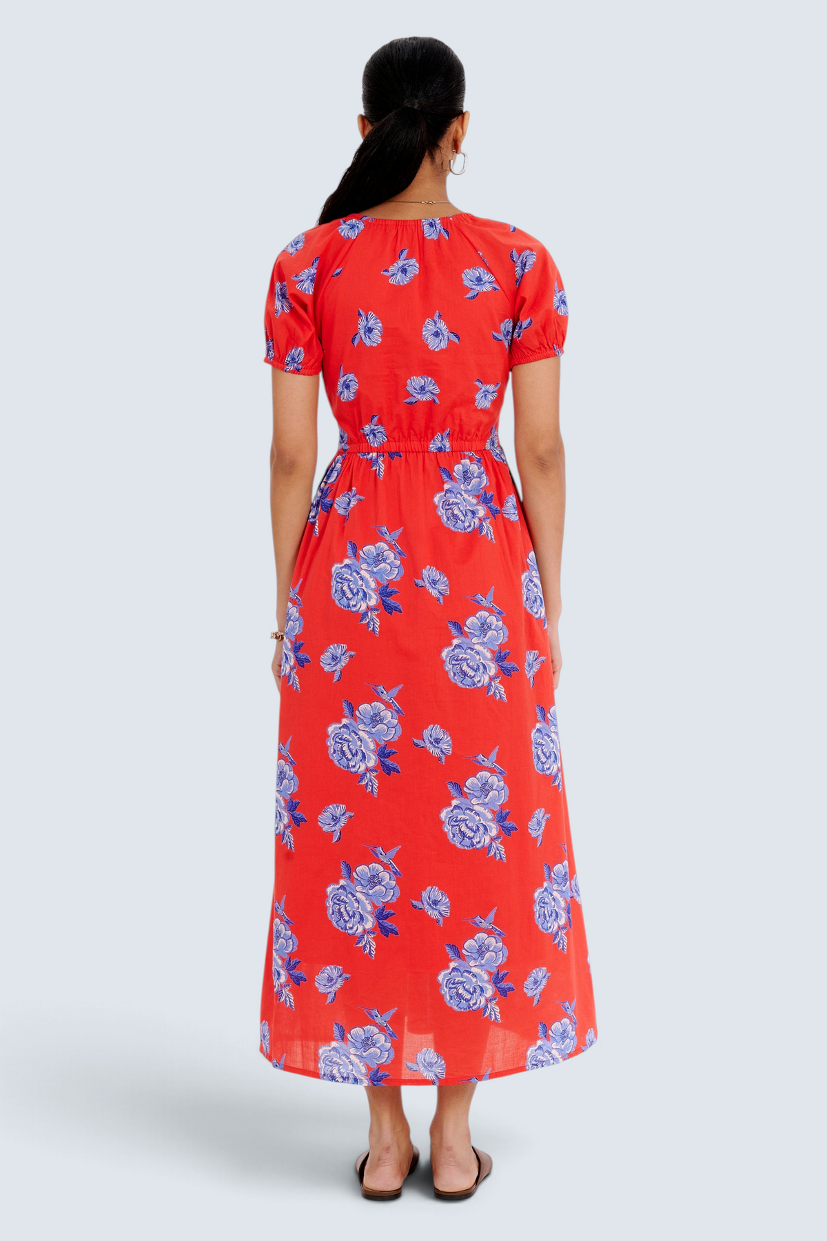Banjanan Norma dress in poppy red with blue floral rose print, featuring a drawstring neckline and midi length.