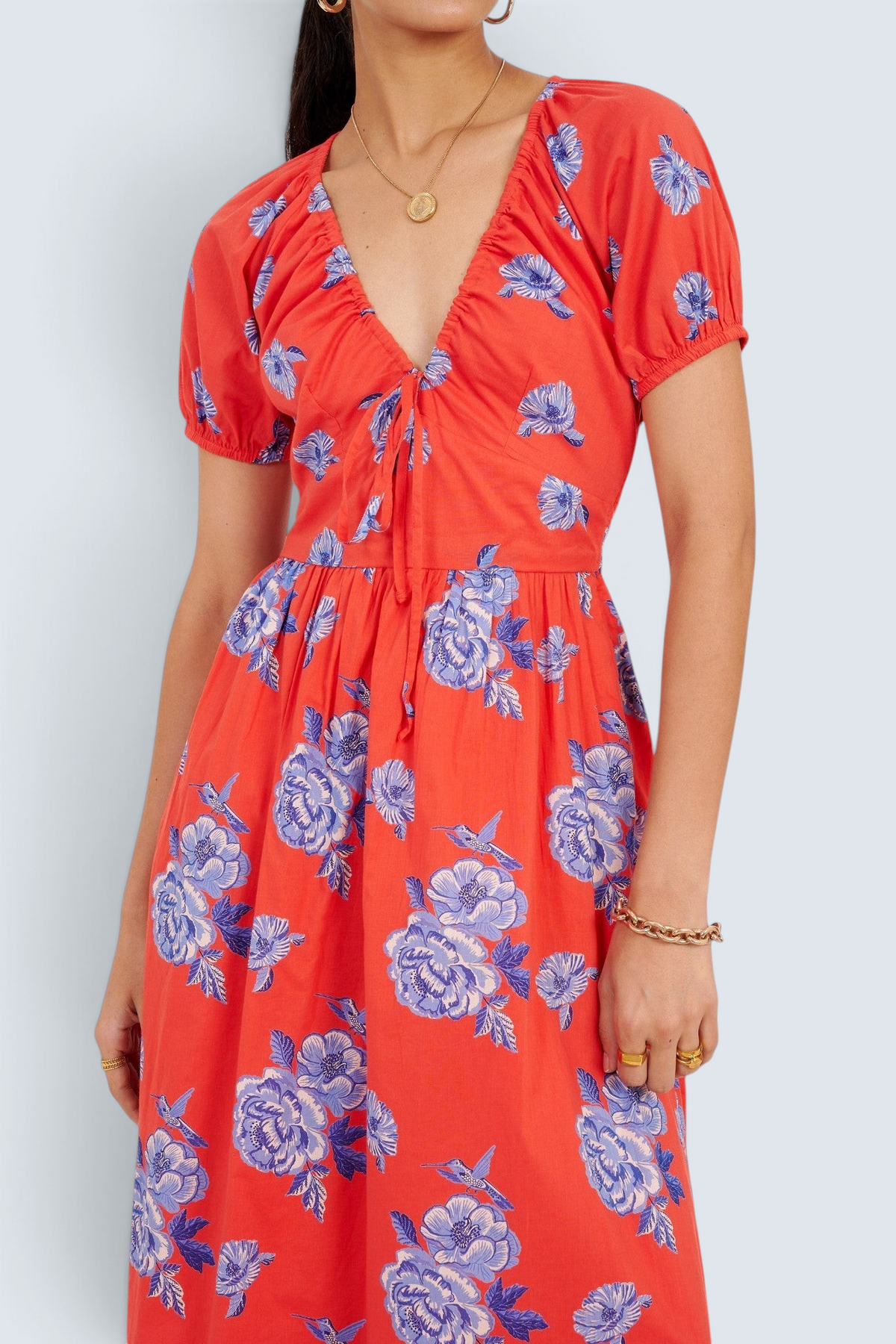 Banjanan Norma dress in poppy red with blue floral and hummingbird print, featuring a drawstring neckline and sleeves.