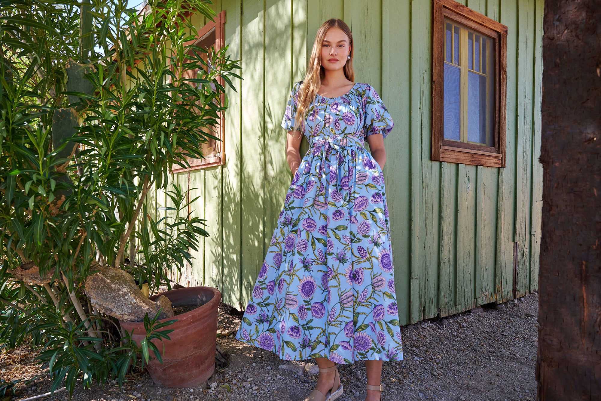 A model standing outside a house wearing Heidi Dress in Protea print.