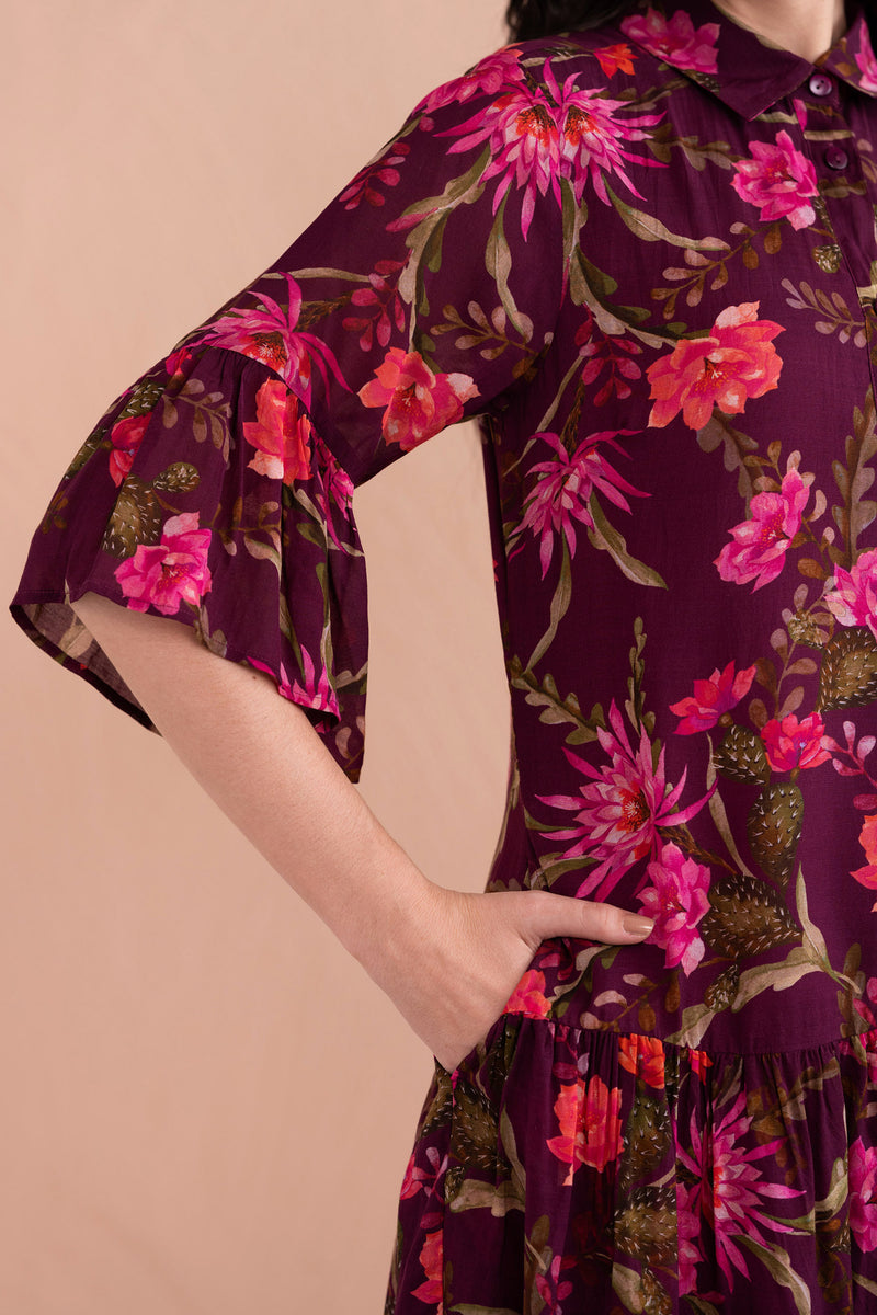 Close up of woman wearing Hydra Mini Dress in Desert Rose Dusk print, Showing details of bell sleeves, slightly dropped waist, and side-seam pockets in lightweight viscose voile.