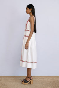 Side view of model standing straight wearing a midi length Rasia Dress in Calico Embroidery Ivory Flame.