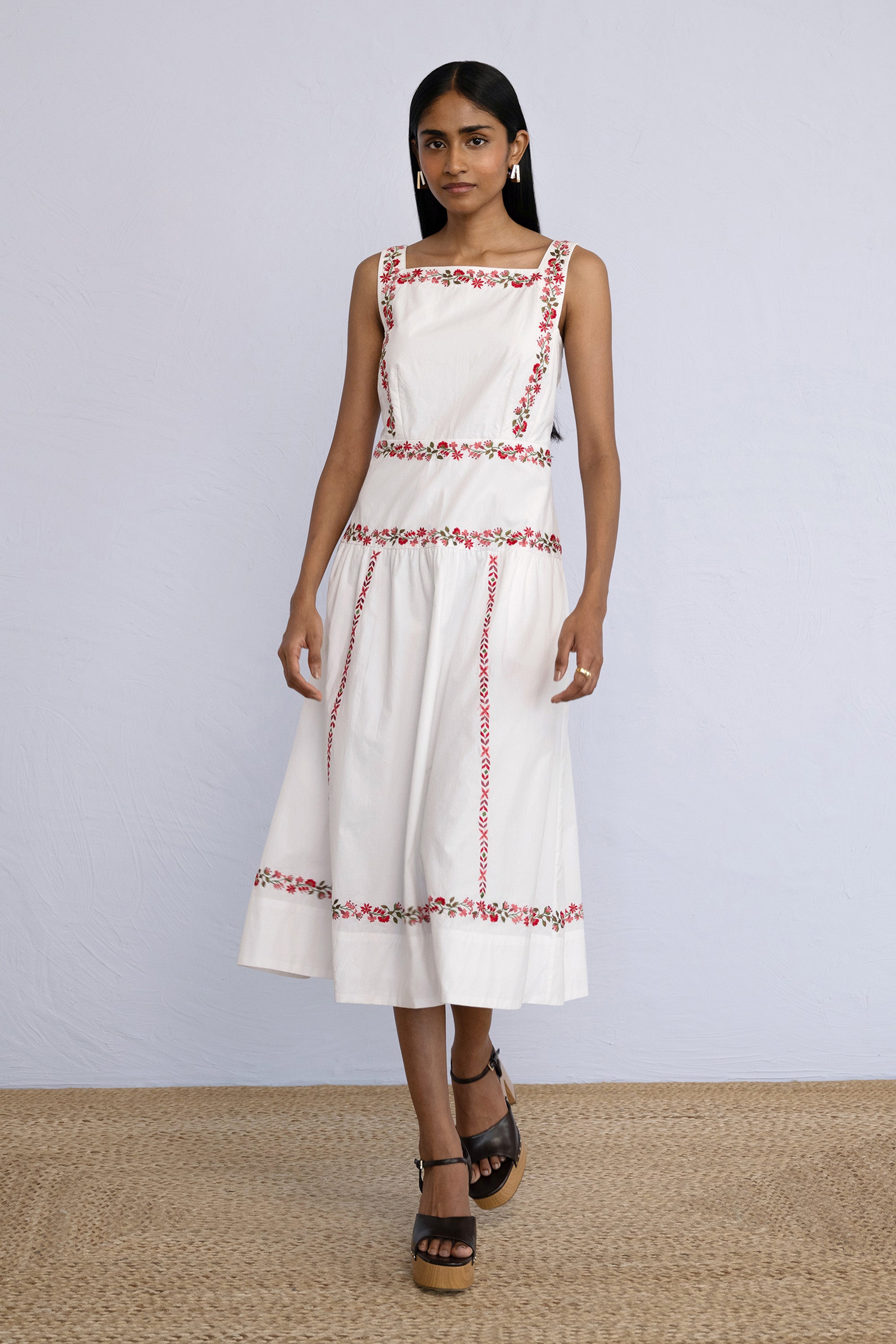 Front view of model stepping forward wearing a midi length Rasia Dress in Calico Embroidery Ivory Flame.