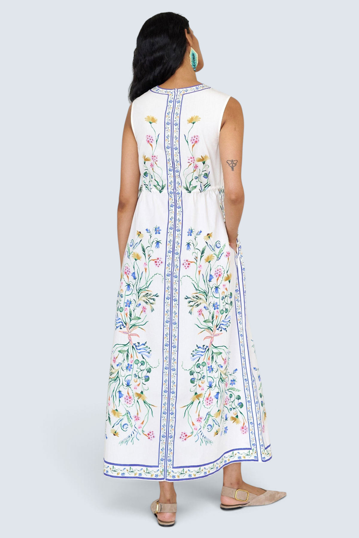 Back view of a woman standing wearing the Rhonda column dress in Tidepool print, featuring side drawstrings with gold caps, front keyhole button, and side-seam pockets.