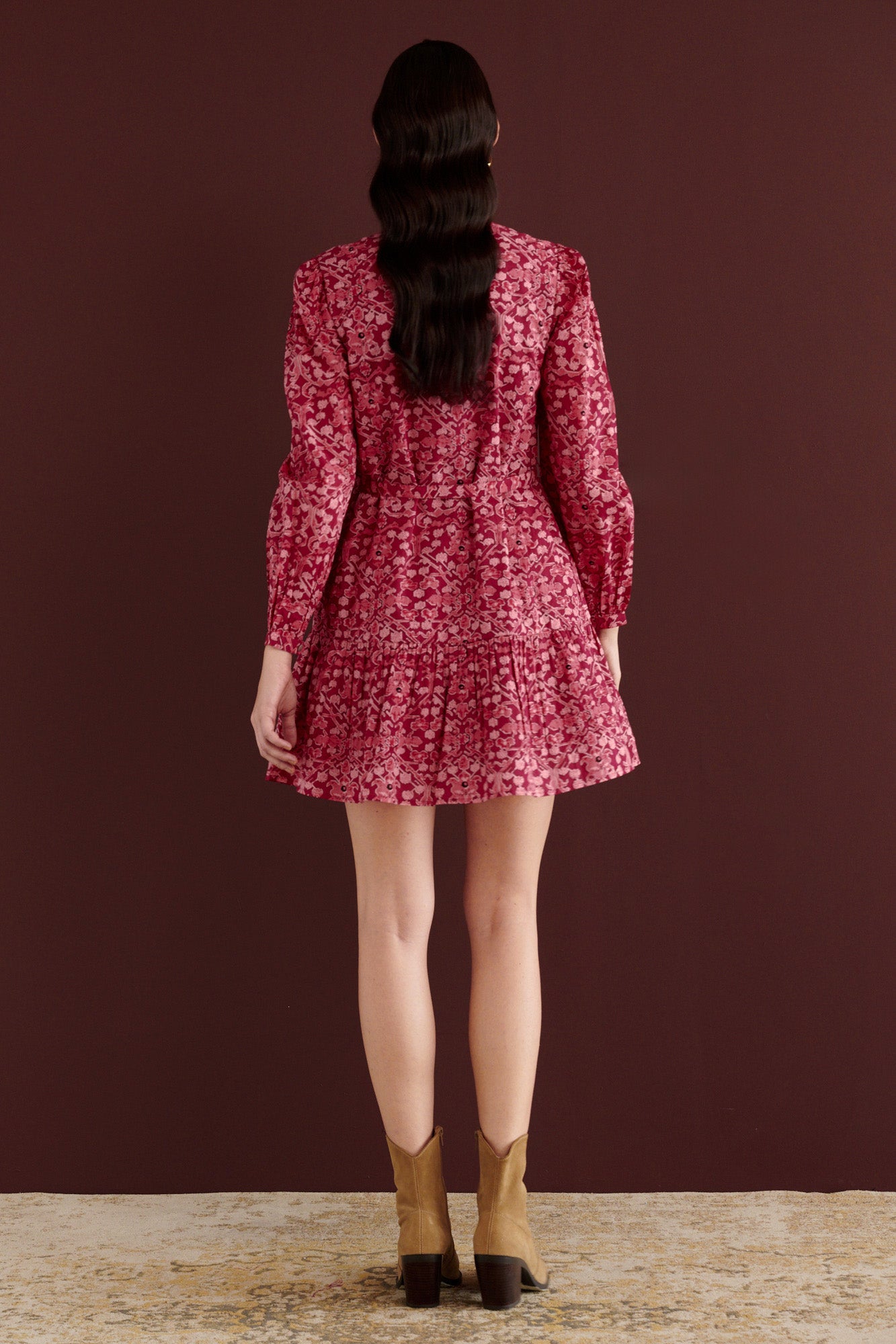 Back view of woman standing. She is wearing the Roma mini dress in Ottoman print, with wrist-length sleeves, smooth cotton cambric, detachable belt, side-seam pockets, and fully lined construction in rich Berry red color.