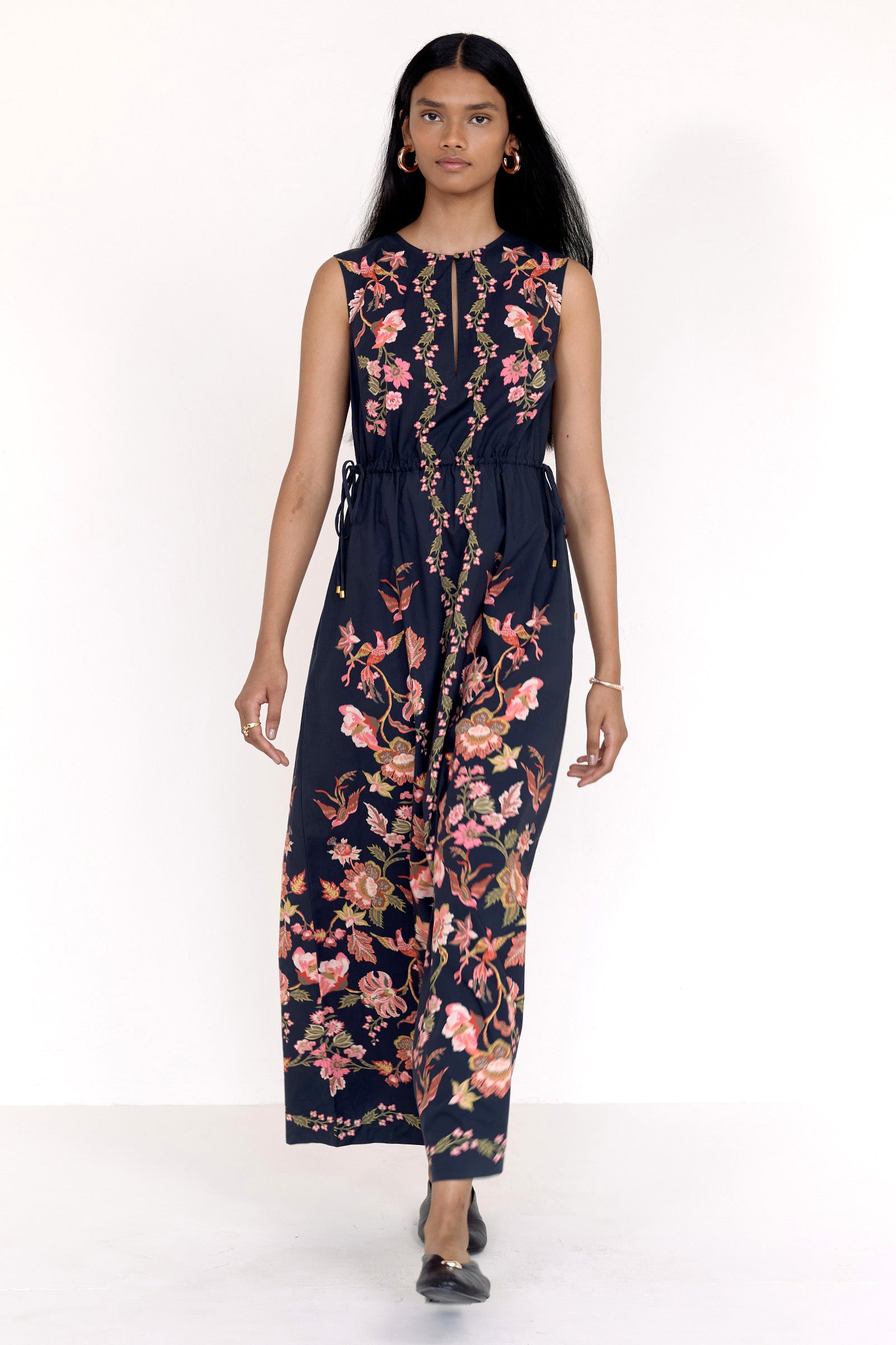 Front view of model walking forward. She is wearing the Rhonda dress in Chintz Jet. It  features a crewneck with keyhole detail, adjustable drawstring sleeves, column silhouette, and vintage-inspired floral and bird print.