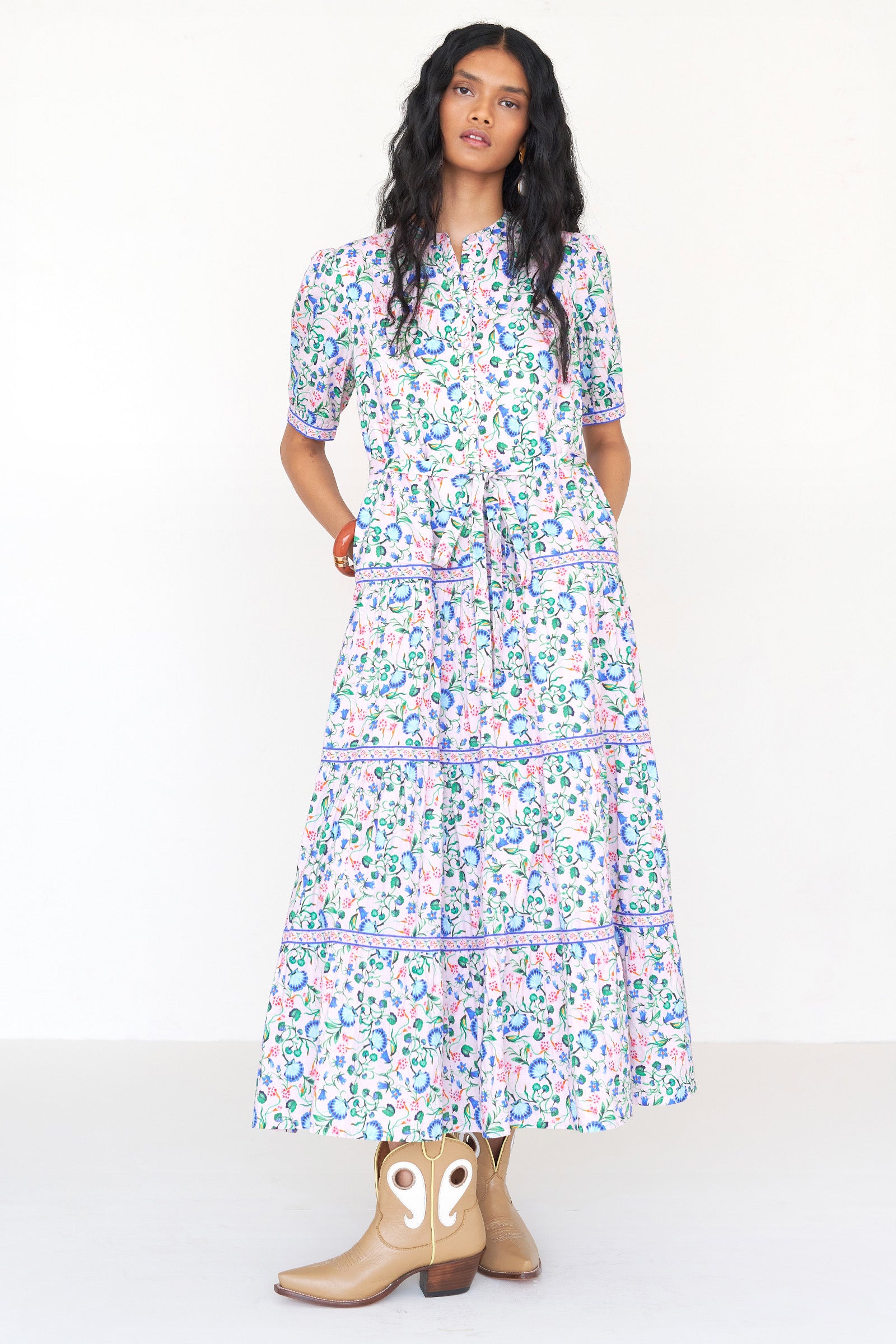 Front view of a woman standing wearing the Saylor dress in Clam Garland print. It features a stand collar, contrast trim, tiered skirt, detachable belt, and full-length shirtdress silhouette.