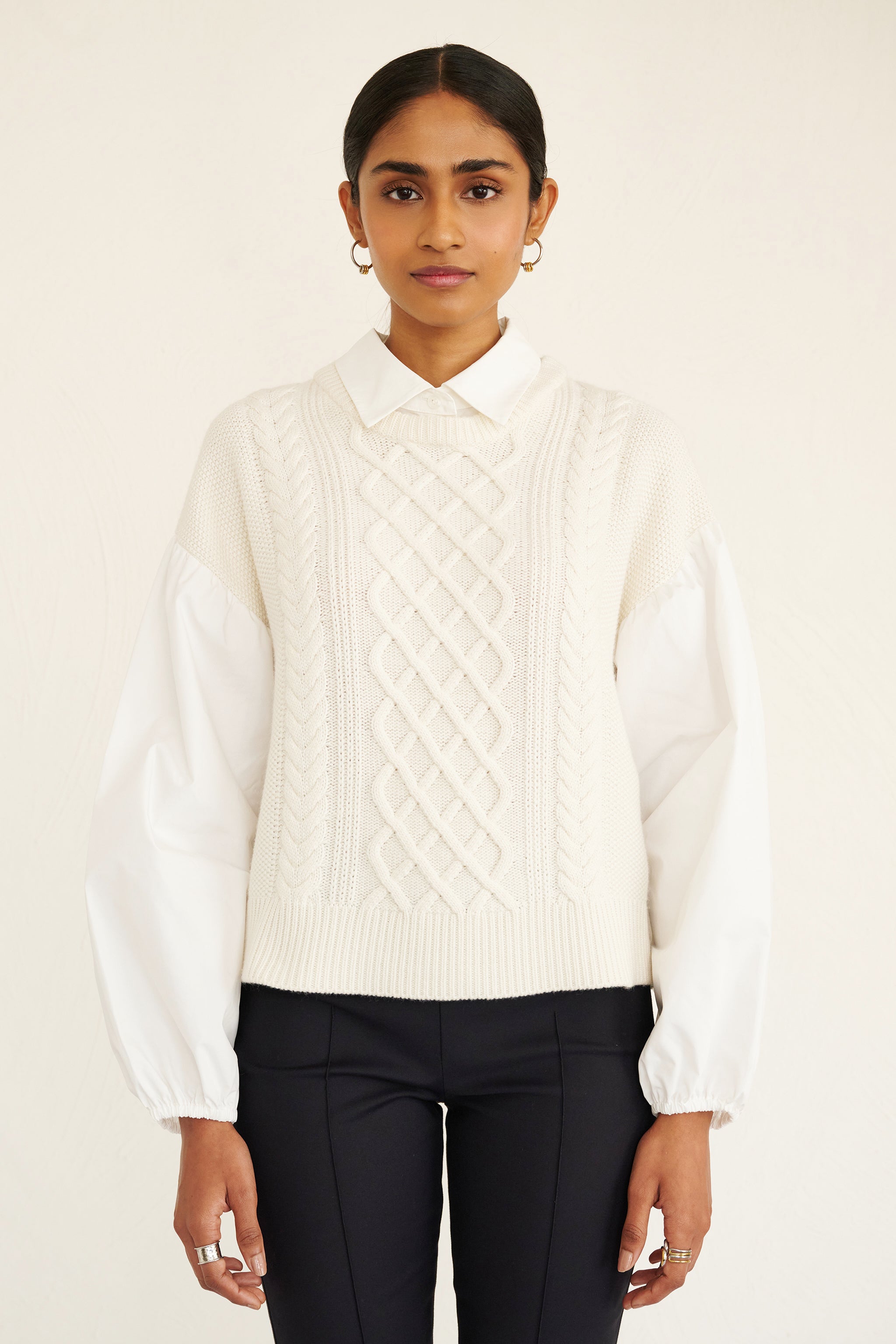 Front view of woman wearing a cable knit sweater with poplin shirt collar and sleeves, featuring elastic cuffs for shape and a layered look.