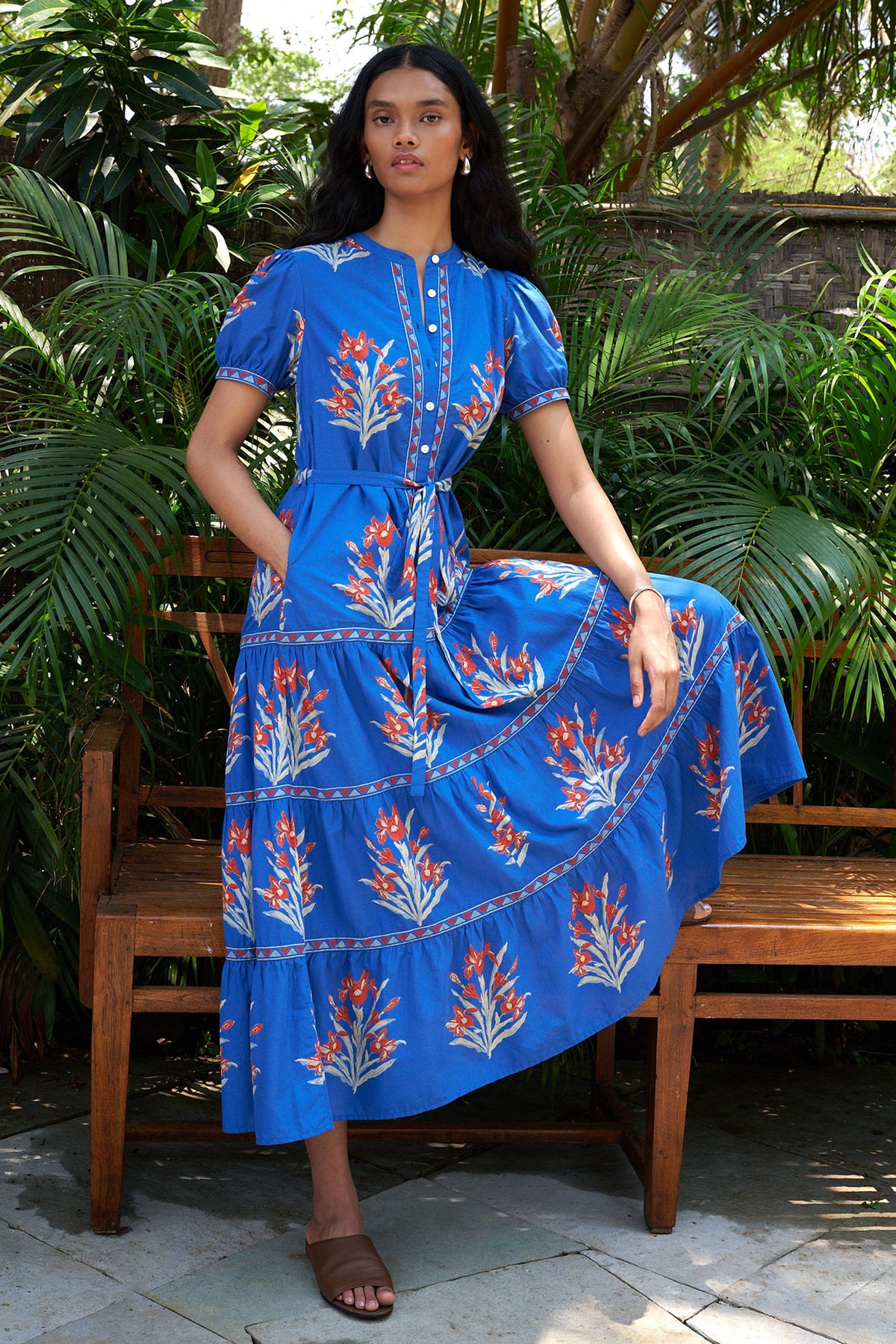 Woman wearing a Saylor dress in Brigitte Nautical with floral patterns standing on tropical setting.