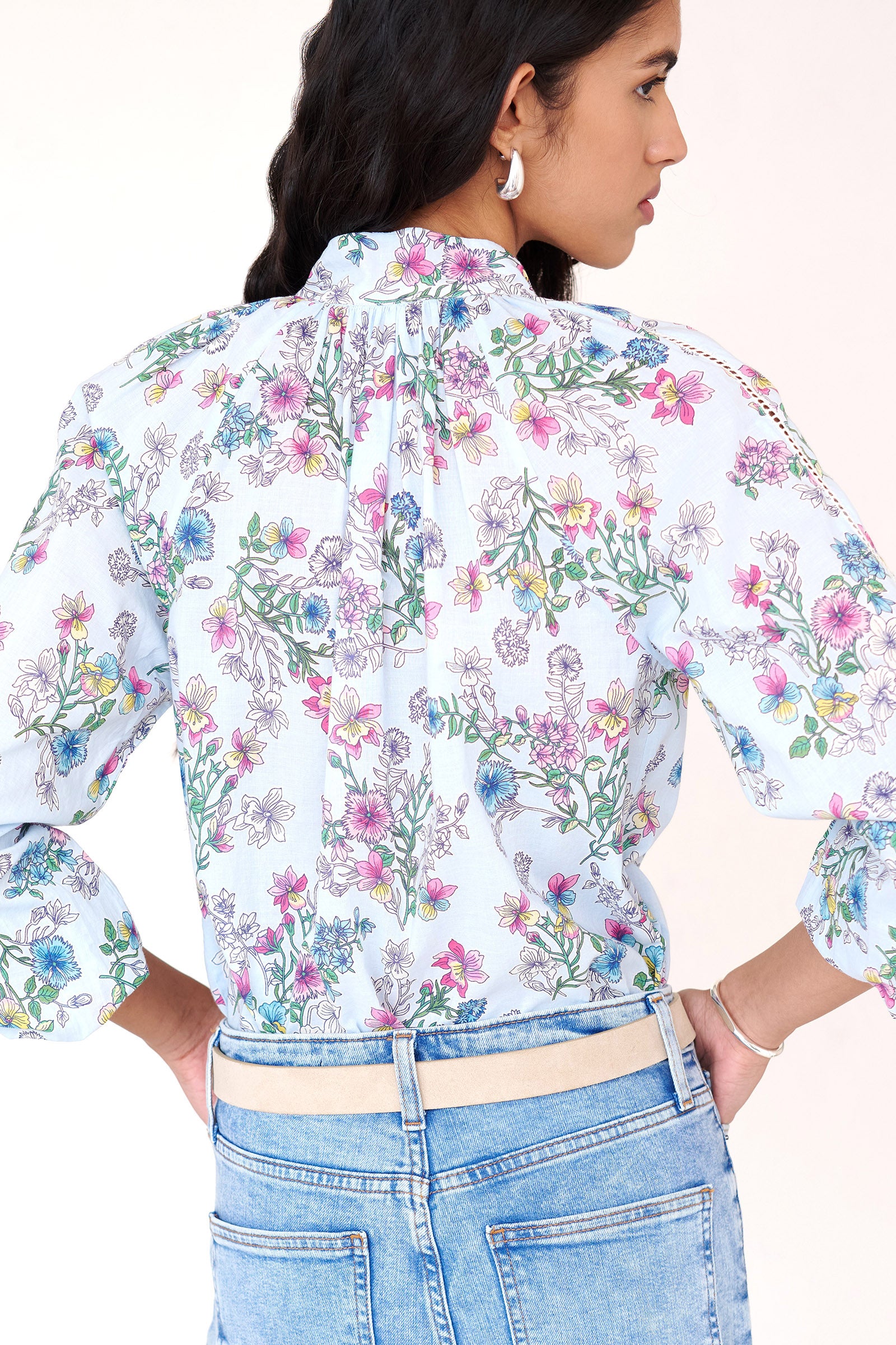 Back view of woman wearing the Tara shirt with a stand collar, elasticated button loops, lace trim detailing, and the Burdock floral print in imperial color.