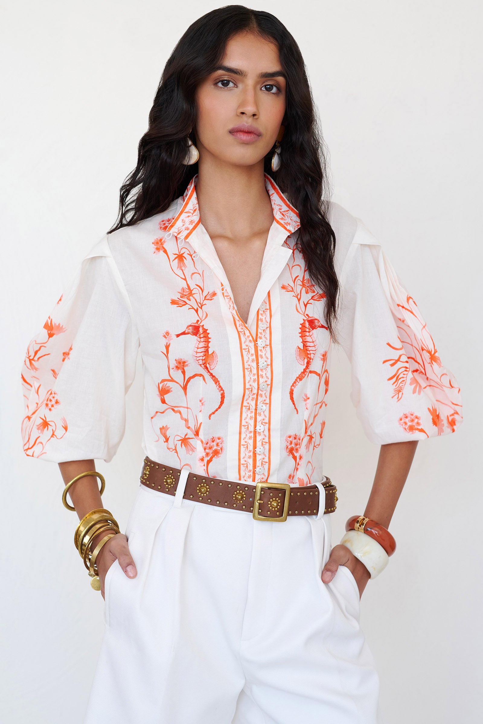 Front view of woman wearing the Tilly top with a stand collar, fabric-covered buttons, elegant sleeves, and the Tidepool print featuring seahorses, shells, and oyster catchers.