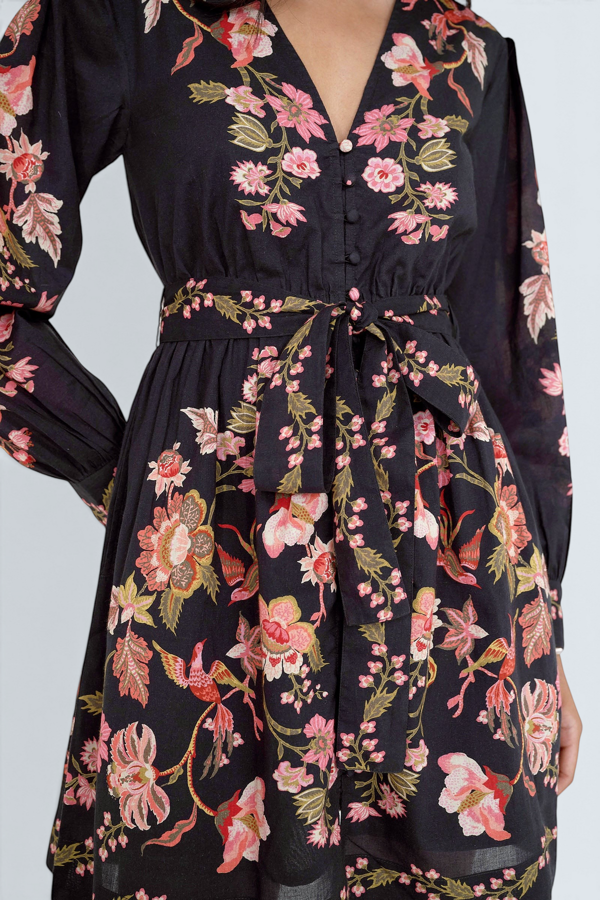 Close up of the Anne mini dress in Chintz print. It features long sleeves, an elasticated waist, fabric-covered buttons, a fabric belt, and side-seam pockets.