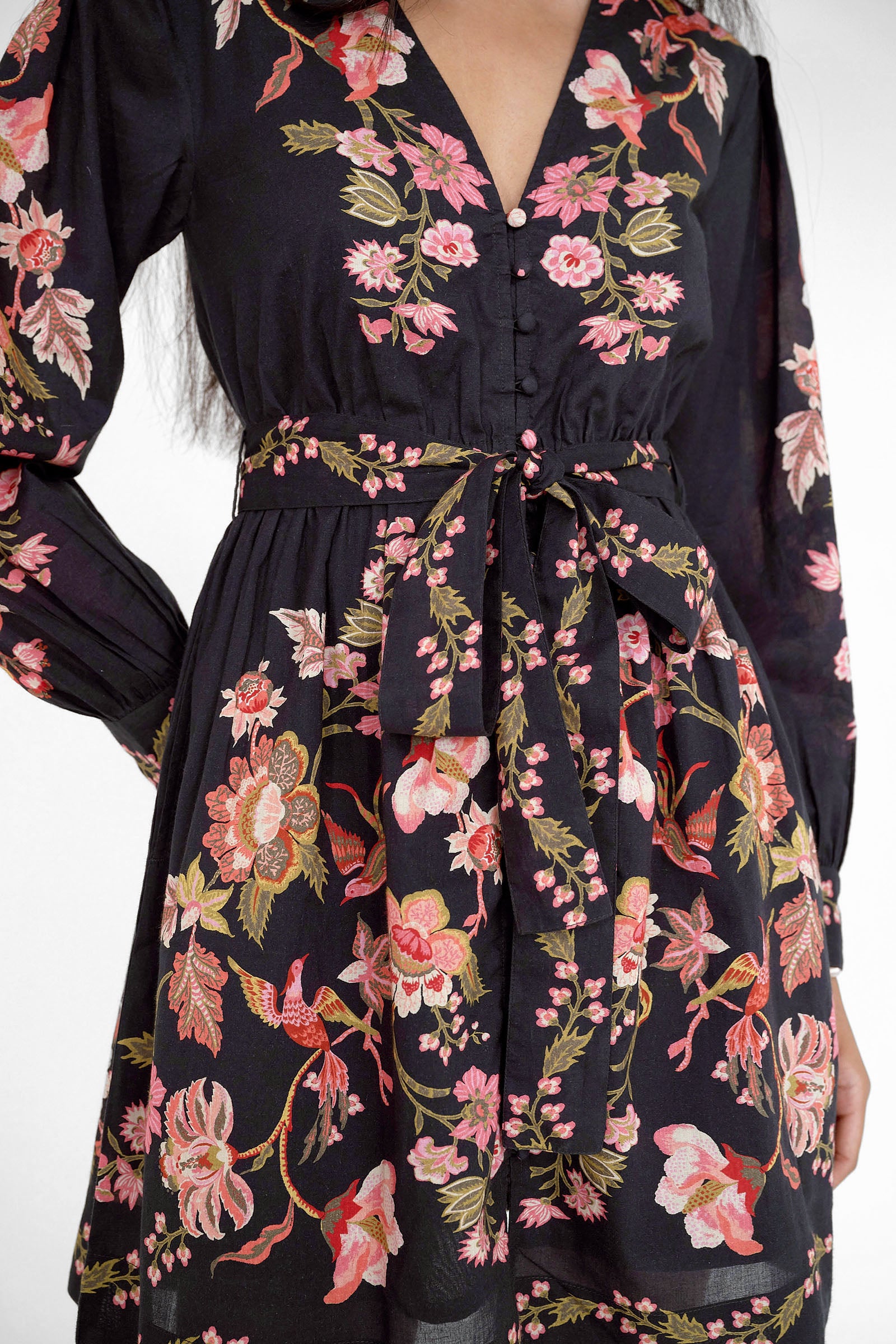 Close up of the Anne mini dress in Chintz print. It features long sleeves, an elasticated waist, fabric-covered buttons, a fabric belt, and side-seam pockets.