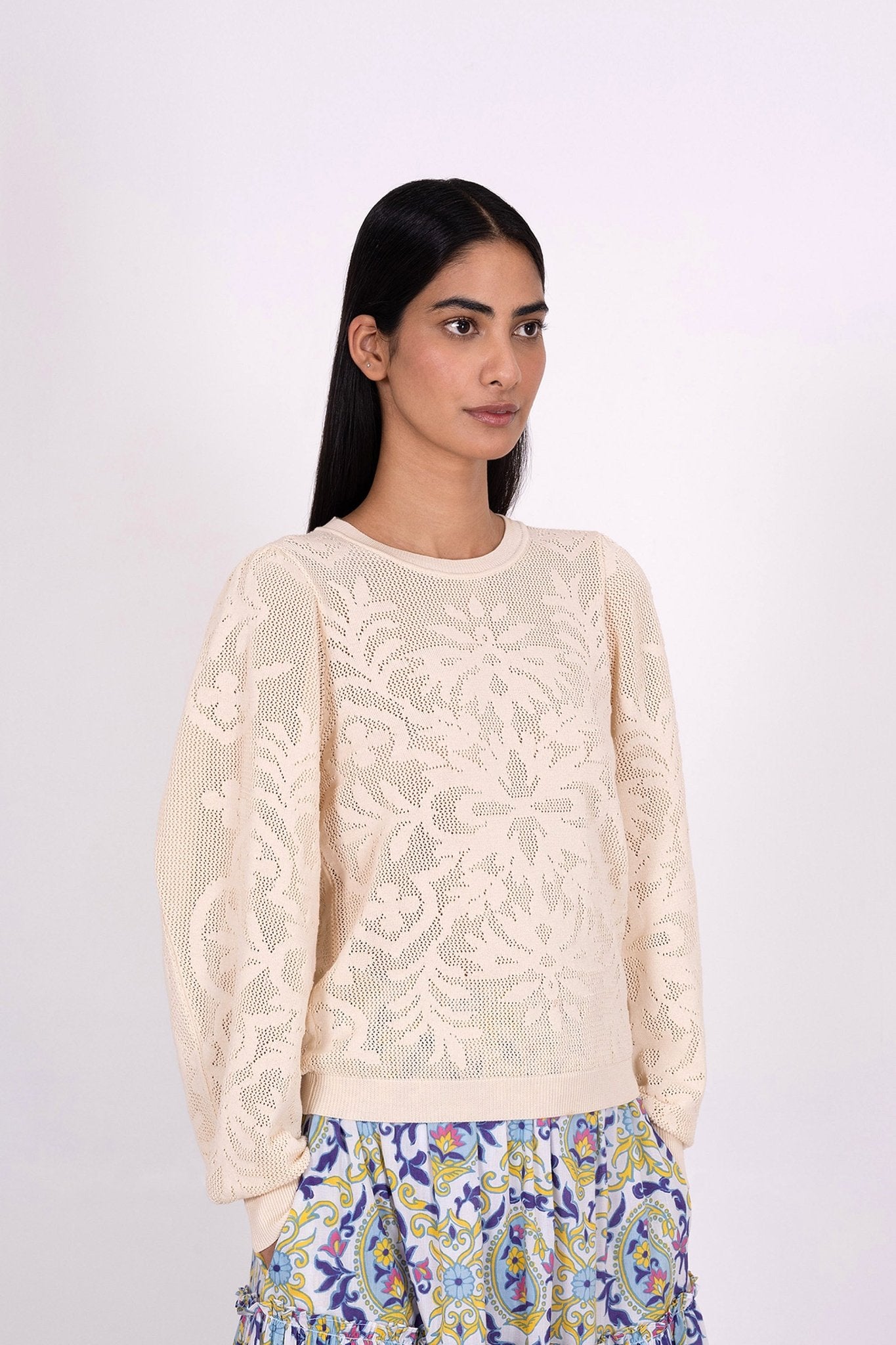 Side view of woman wearing the Astrid Doge's crew neck sweater, a white knit resembling lace. Perfect for transitional weather, it pairs well with skirts or pants.