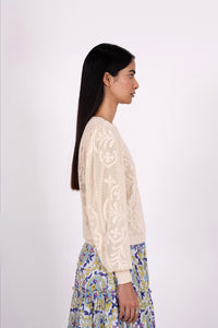 Side view of woman wearing the Astrid Doge's crew neck sweater, a white knit resembling lace. Perfect for transitional weather, it pairs well with skirts or pants.