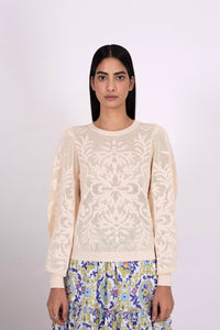 Front view of woman wearing the Astrid Doge's crew neck sweater, a white knit resembling lace. Perfect for transitional weather, it pairs well with skirts or pants.