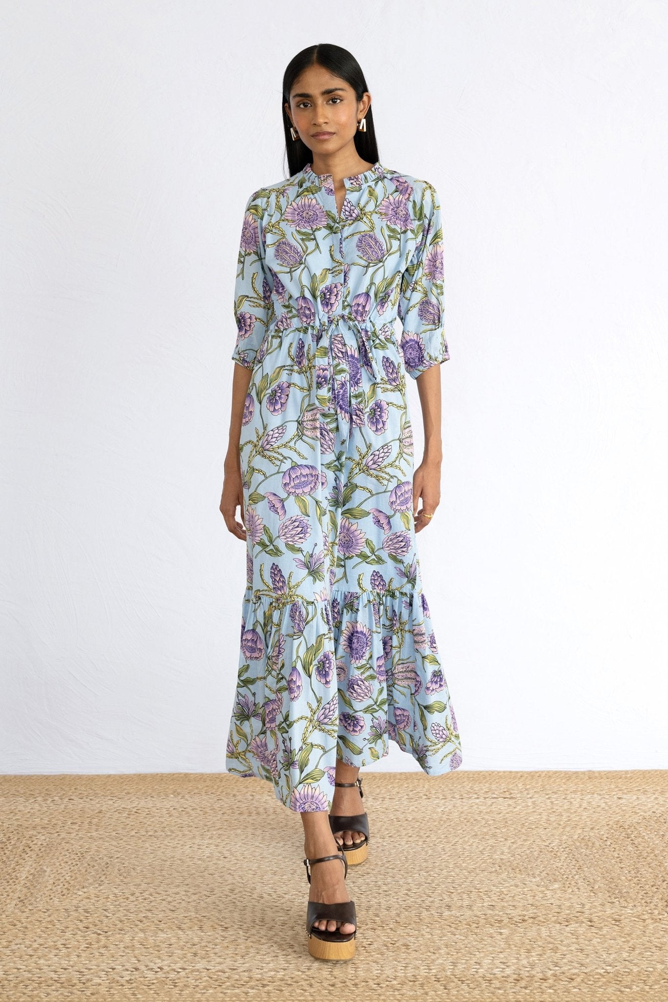 Front view of model stepping forward wearing Betty Dress in Protea Orchid print. 