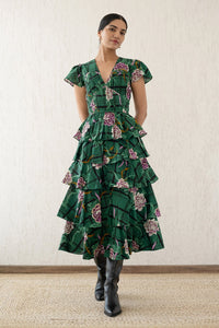  A front view of a woman wearing the Brigit dress in Tartan Rose print. It features a cascading skirt of tiered ruffles, pin tucks under bust and waist, a V-neck, and cap sleeves.